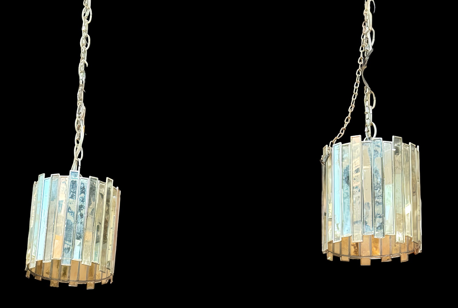 Pair of Vintage Mirrored Pendant Lights.: The pair of pendant lights feature drum-style shades composed of rectangular mirror panels of unequal lengths. They measure 8" tall and 7 1/4" in diameter. There is some (likely purposeful)
