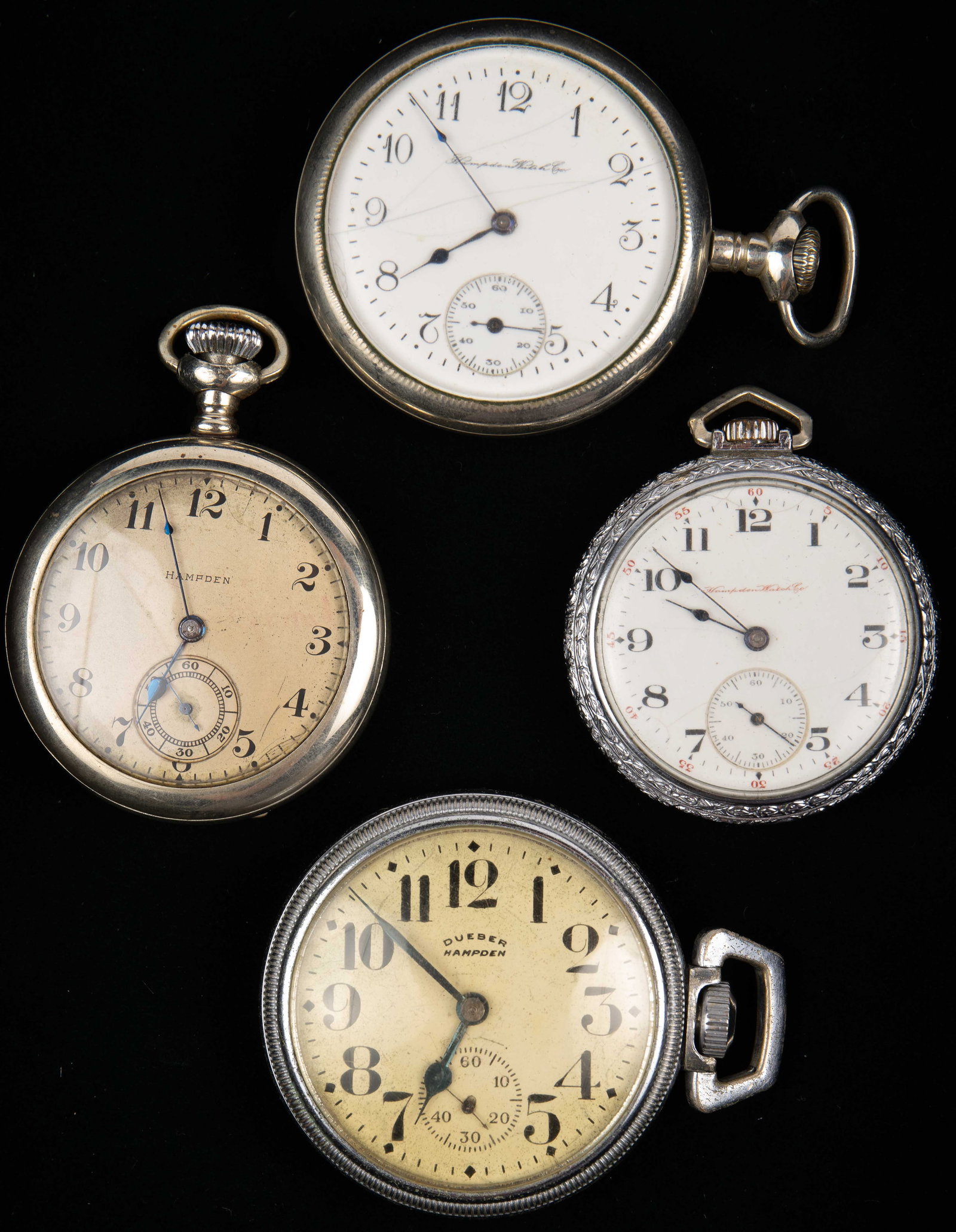 Lot: 4 Hampden Pocket Watches, 1 w/ Crystal Back.: The lot contains 4 Hampden pocketwatches in nickel or metal cases. One of the items has a crystal back, and one is marked Dueber on the face. All of them tick. The smallest case measures 1 3/4", and t