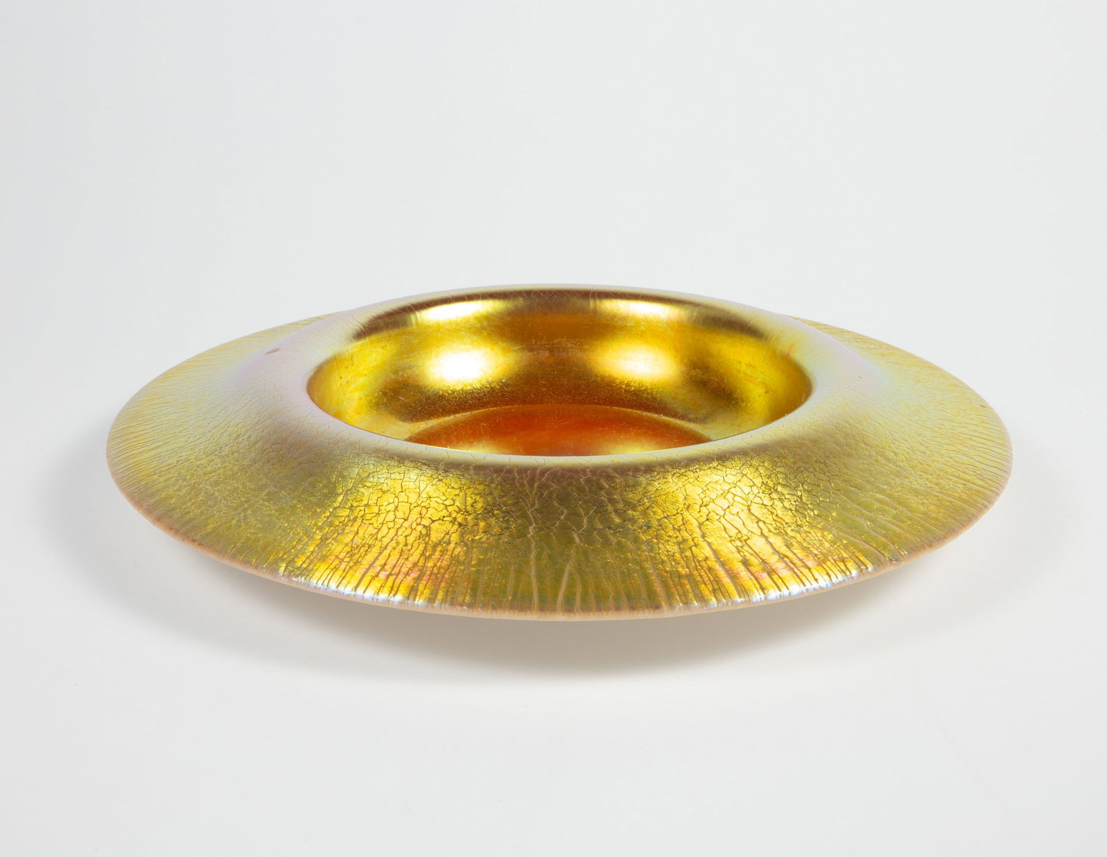 Unsigned Tiffany Gold Aurene Centerpiece Bowl.: The bowl is attributed to Tiffany Studios. It has a wide lip angled down. It appears to be unsigned. It measures 14 1/8" in diameter. The bowl has some scratches and stains. Otherwise, it is in