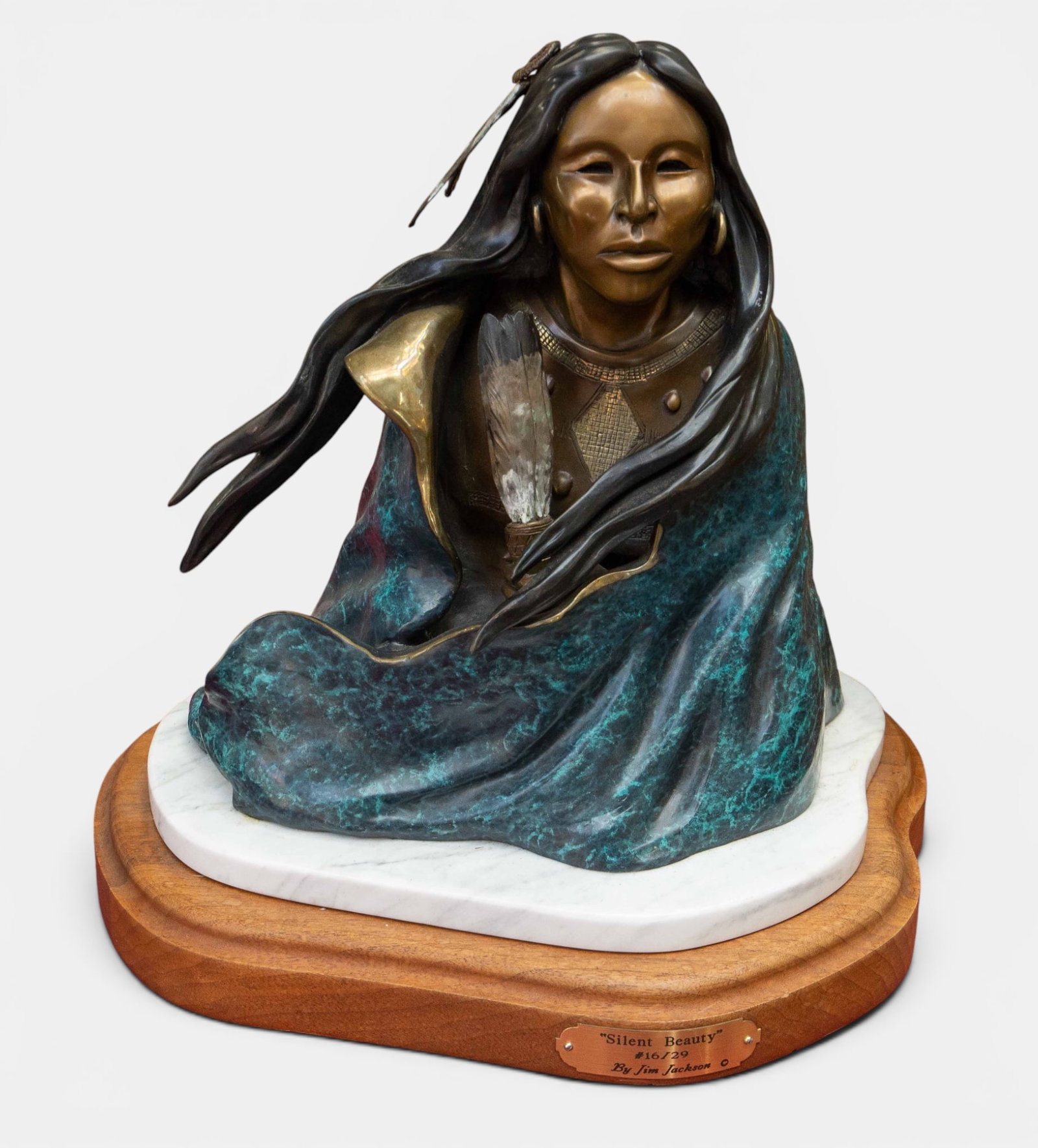 "Silent Beauty" American Indian Bust- Jim Jackson.: This bronze bust sits atop an attached marble and wood base. The back is signed, and numbered 16/29. There is some white residue on her feathers, but overall, the piece looks to be in very nice