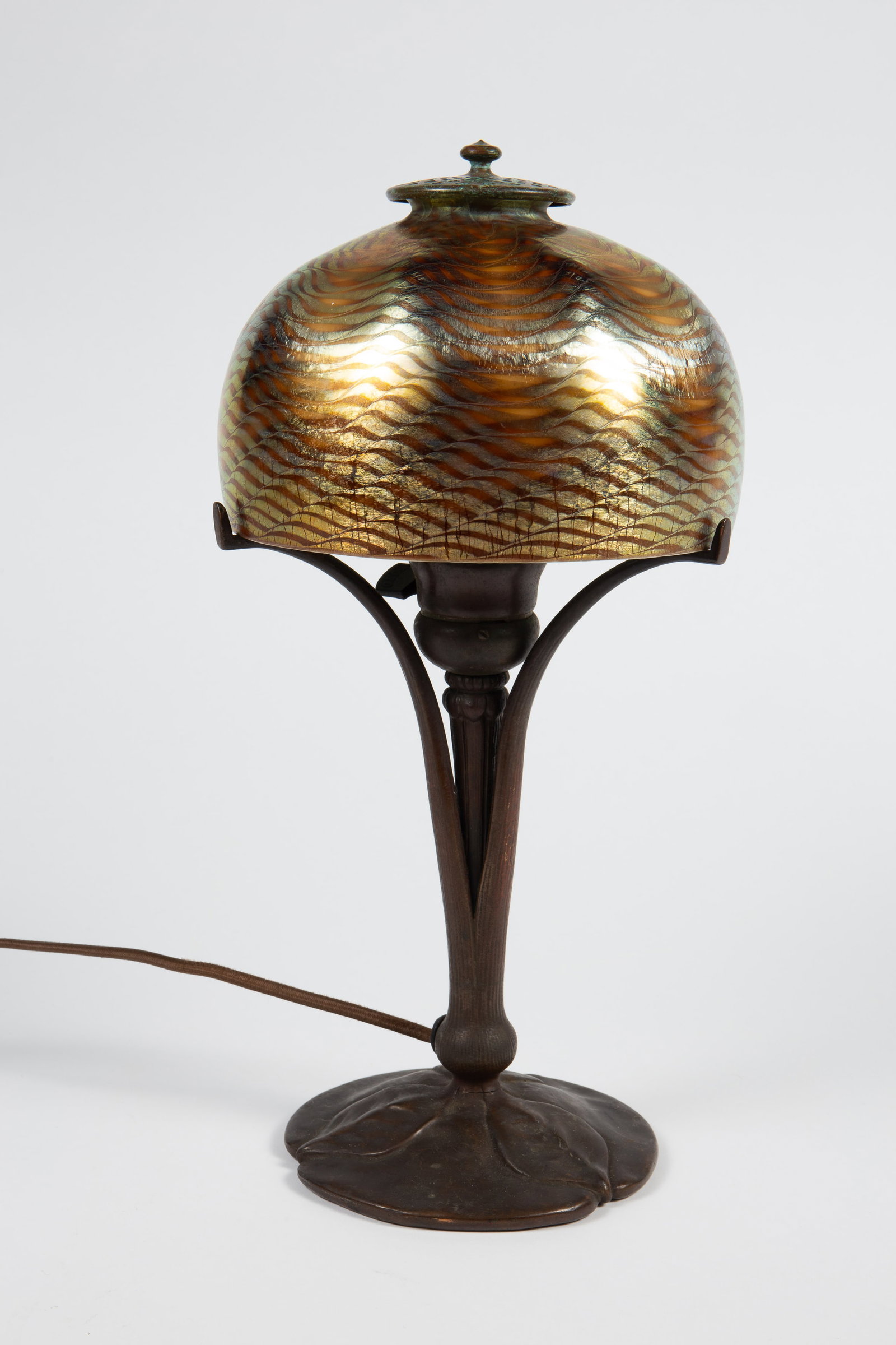 Tiffany Favrile Damascene Wave Bronze Lamp - As Is: The small desk lamp is composed of a bronze base with leaf designs, and 3 arms that hold the domed shade. The shade, which boasts a gold iridescent "Damascene" wave pattern, is signed L.C.T. Favrile o