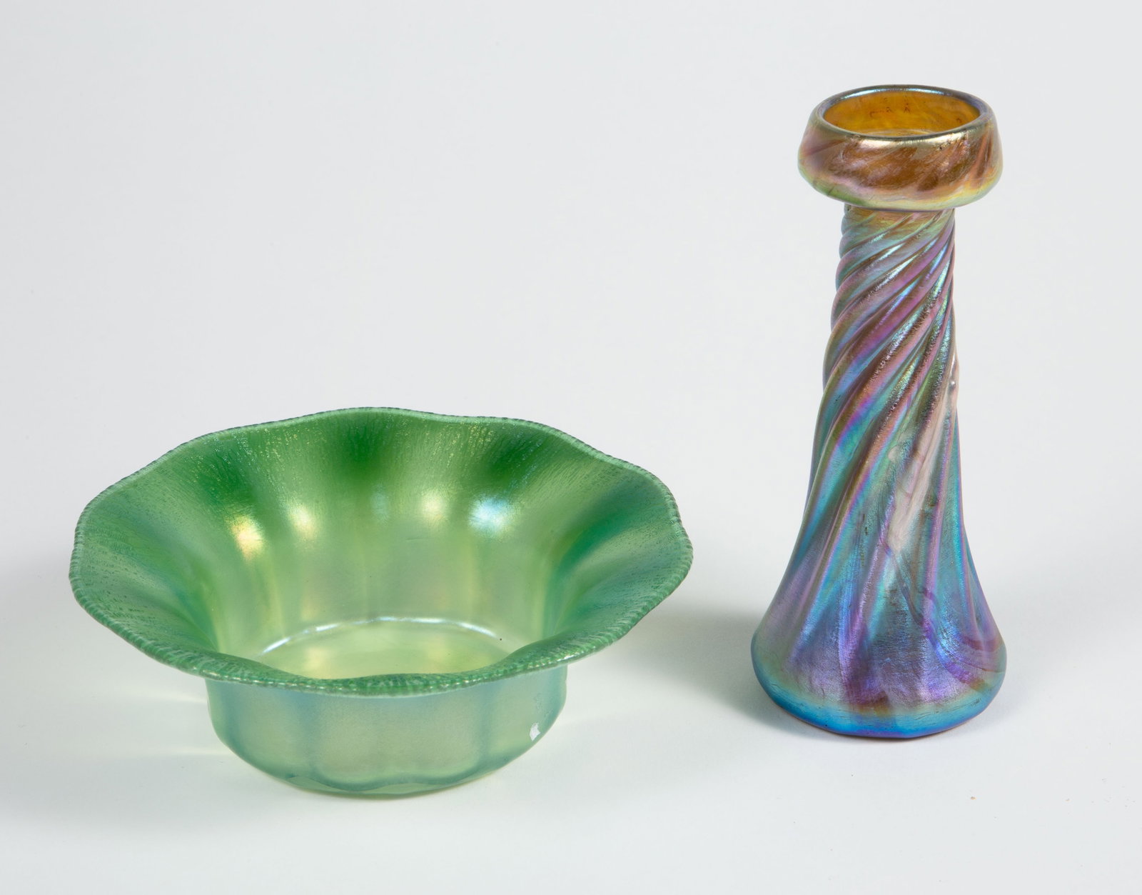 Lot of 2 L.C.T. Tiffany Favrile Glass Pcs.: The lot includes a twisting candlestick (signed "L.C.T. V7116") and a green pastel finger bowl (signed "L.C. Tiffany - Favrile"). They measure 2 1/8" x 2 1/8" x 5 1/8", and 5 1/8" x 5 1/8" x 1 5/8",