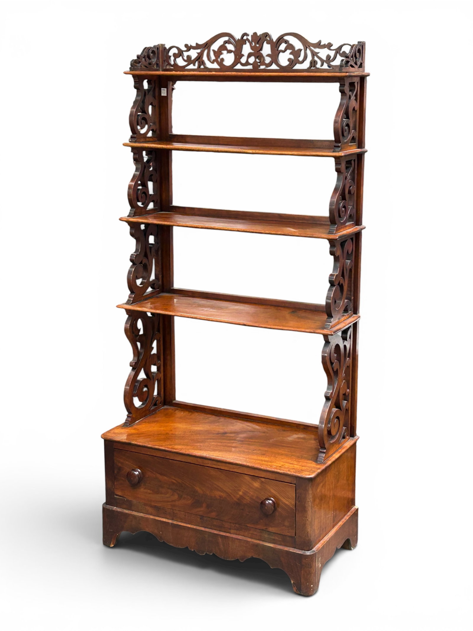 Antique Etagere or Bookshelf.: This shelving unit features four stationary shelves and carved decorations. It has a large bottom drawer with two wood knobs. The piece has intricate cutout work on the sides and back. There are some 