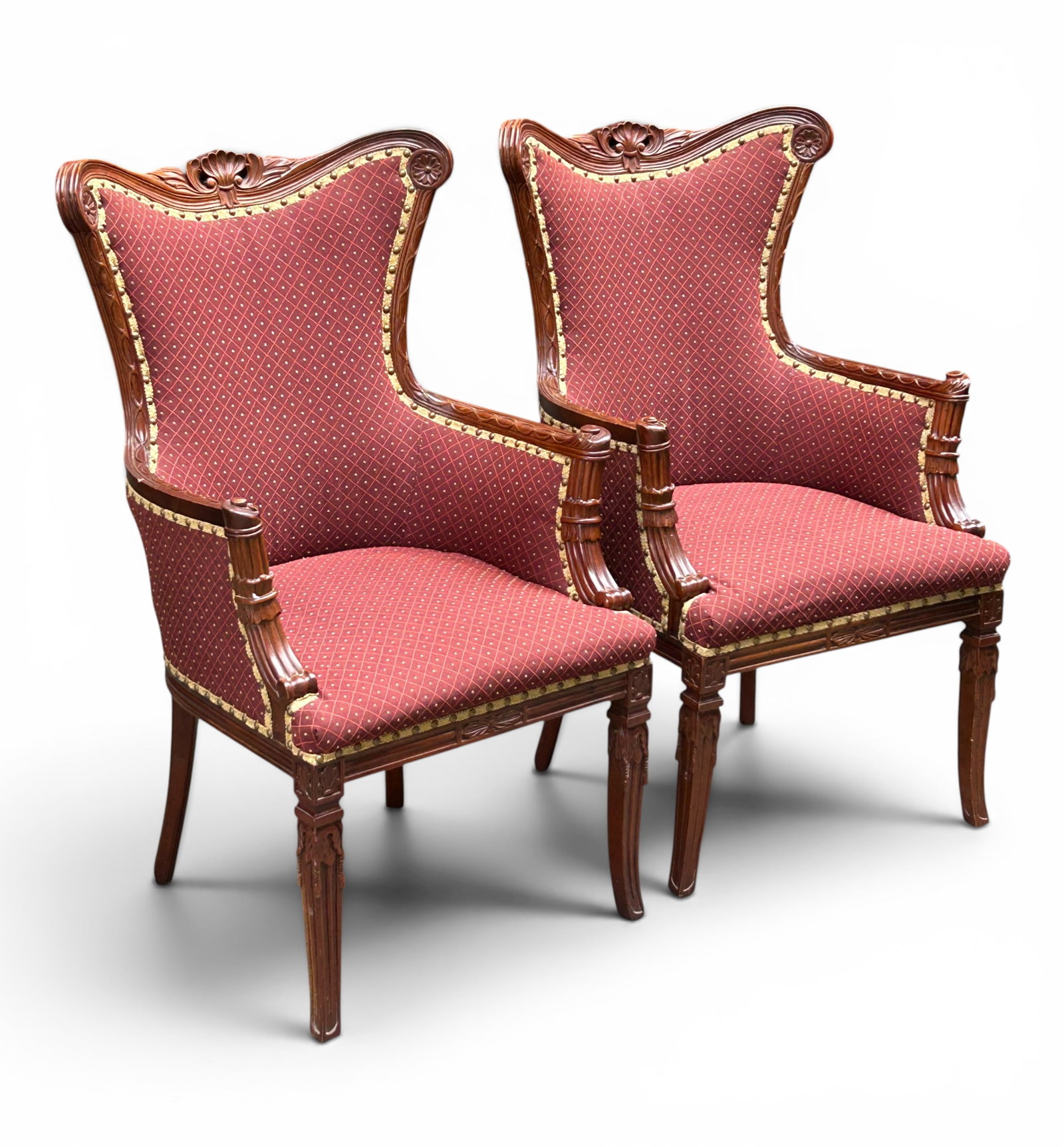 Pair of Louis XV Style Armchairs.: These armchairs each have burgundy upholstery, brass nailhead trim, carved decorative rosettes, a carved shell crest, and carved legs. The bottom of one chair has a Walter E. Smithe label. The seats