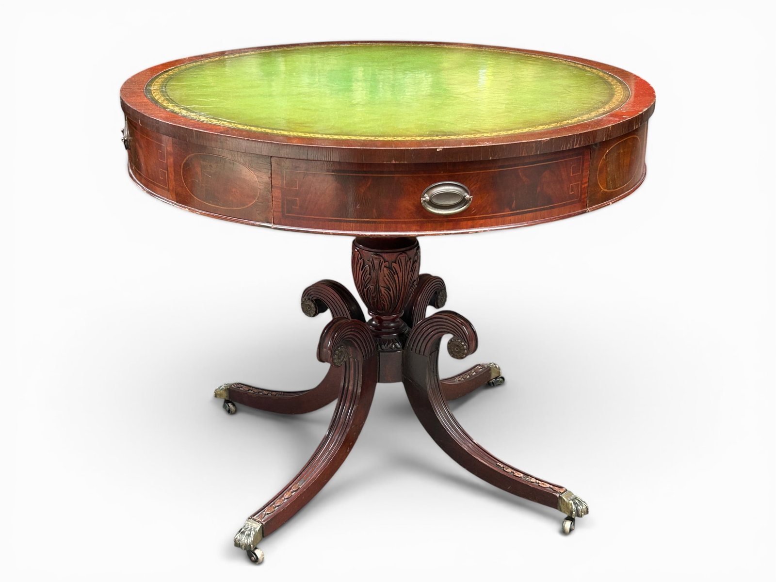Mahogany Drum Table with a Leather Top.: This drum table has one drawer and three faux drawers, all with brass hardware. The green tooled inset top has gold decorative borders. The apron is banded and inlaid. It has a column base on splayed