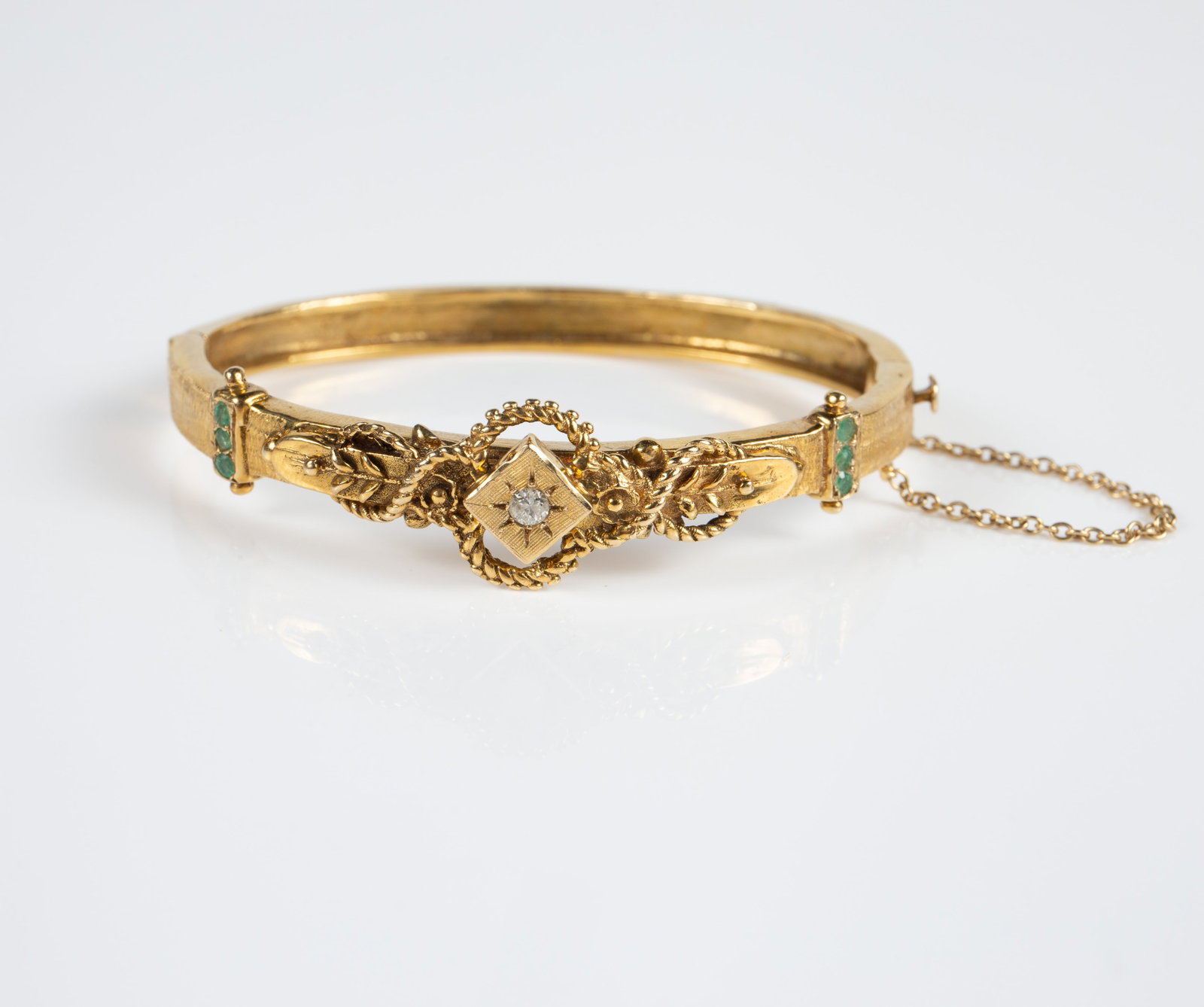 14K Gold Victorian Revival Bracelet w/ Diamond Etc: The bracelet is marked 14K inside the clasp. It features a central round diamond with a diameter of roughly 2 1/2mm, and 3 round green emeralds on each end. The bangle or cuff bracelet measures 2 1/8"