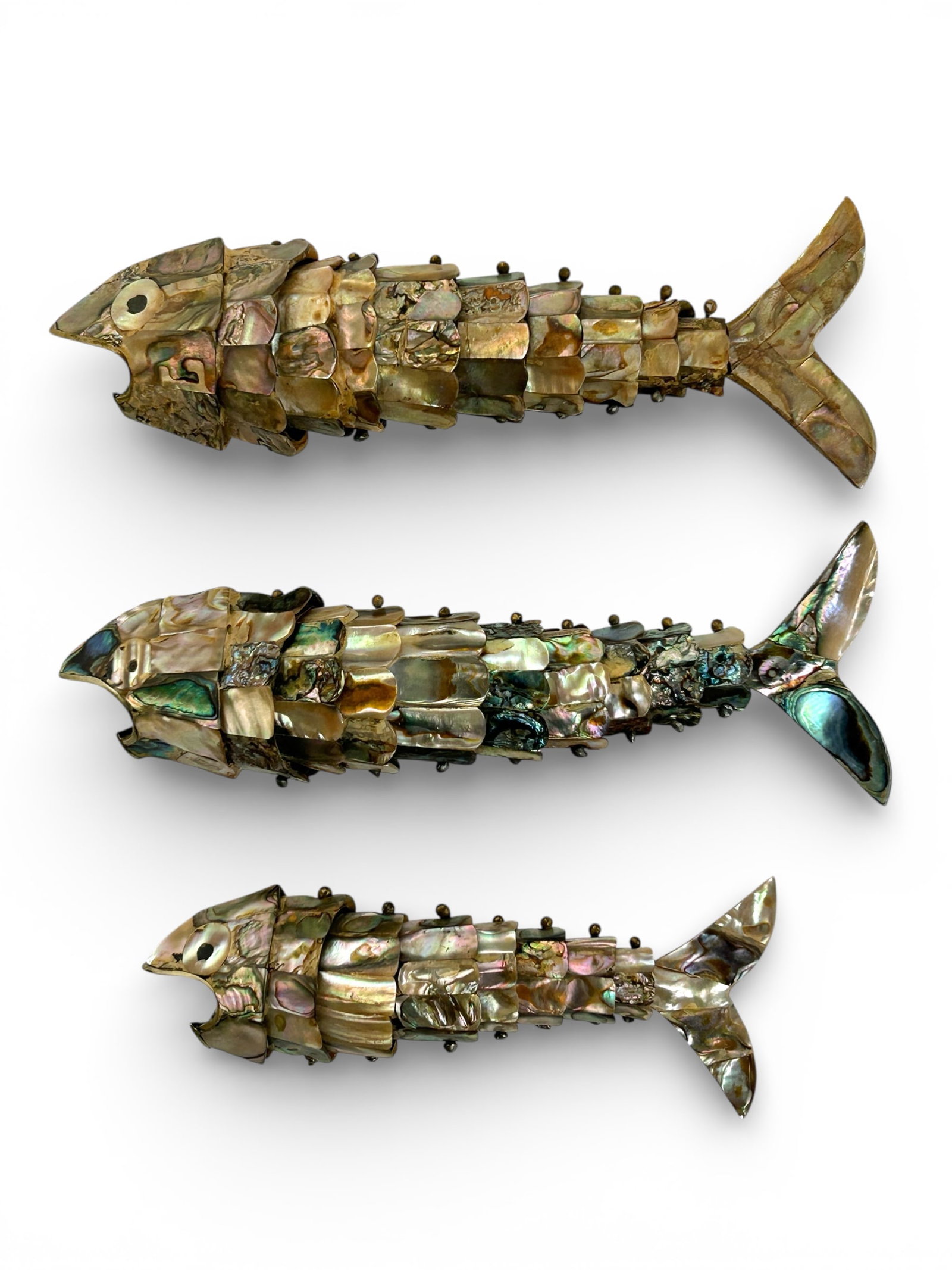 3 Mexican Abalone Articulated Fish Bottle Openers.: The metal and abalone articulated fish bottle openers are in the style of Los Castillos. The largest fish measures 7 7/8" x 1 3/4" 1 5/8", and the smallest piece measures 5 7/8" x 1 5/8" x 1 3/8".