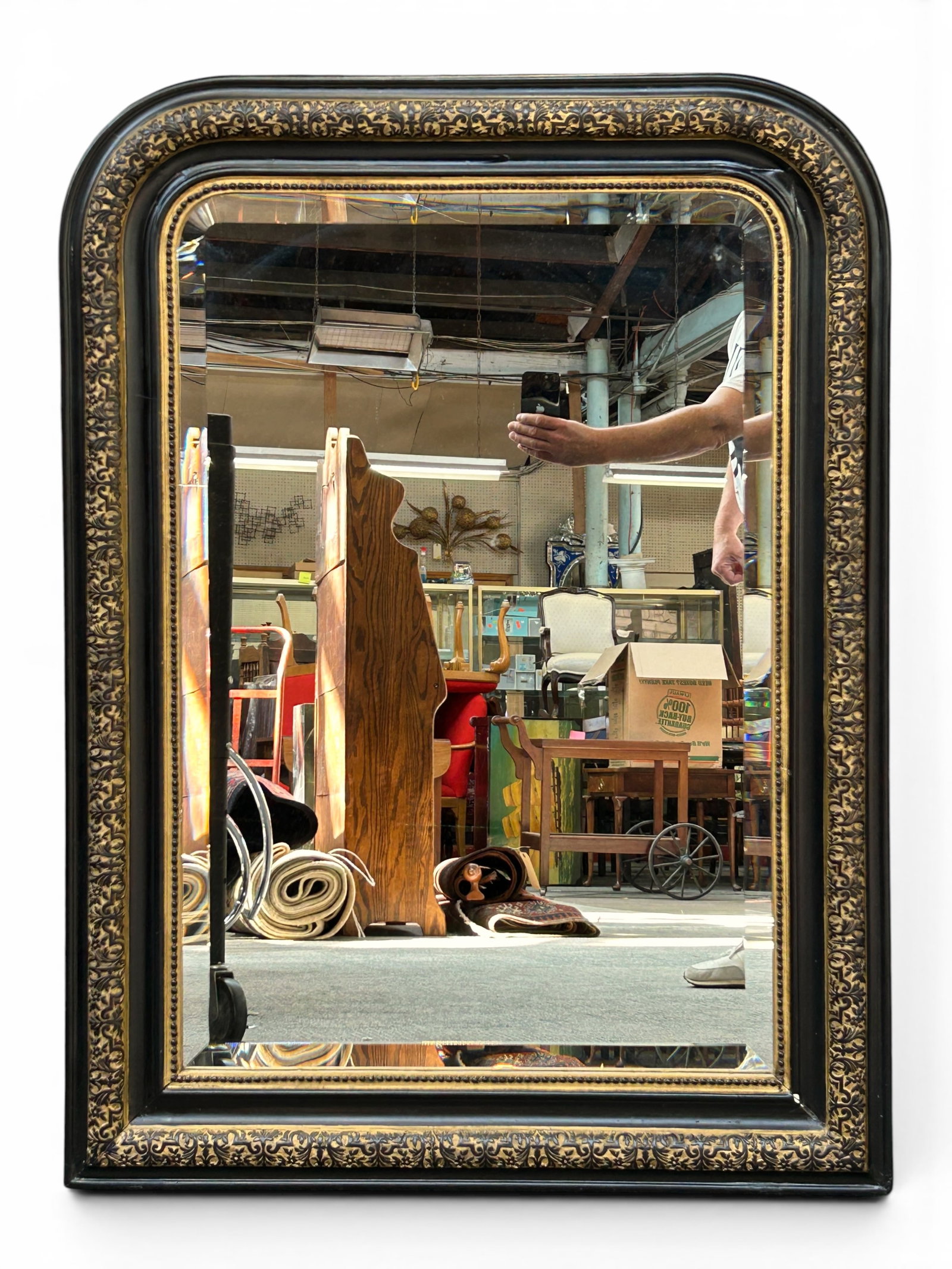 French Louis Philippe Style Wall Mirror.: The beveled mirror has an ebonized frame with a beaded border, gilded floral carvings, scroll work, and a rounded top. It measures 41" tall and 31 1/2" wide. There is a scratch and an indentation in