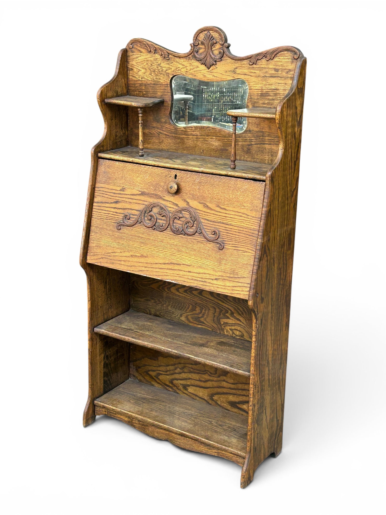 Antique Oak Drop Front Secretary Desk w/ Carvings.: The drop front desk has one shelf on the bottom section, and two small side shelves on the top section, with a bevelled mirror between them. The interior of the desk has 9 organizing compartments.