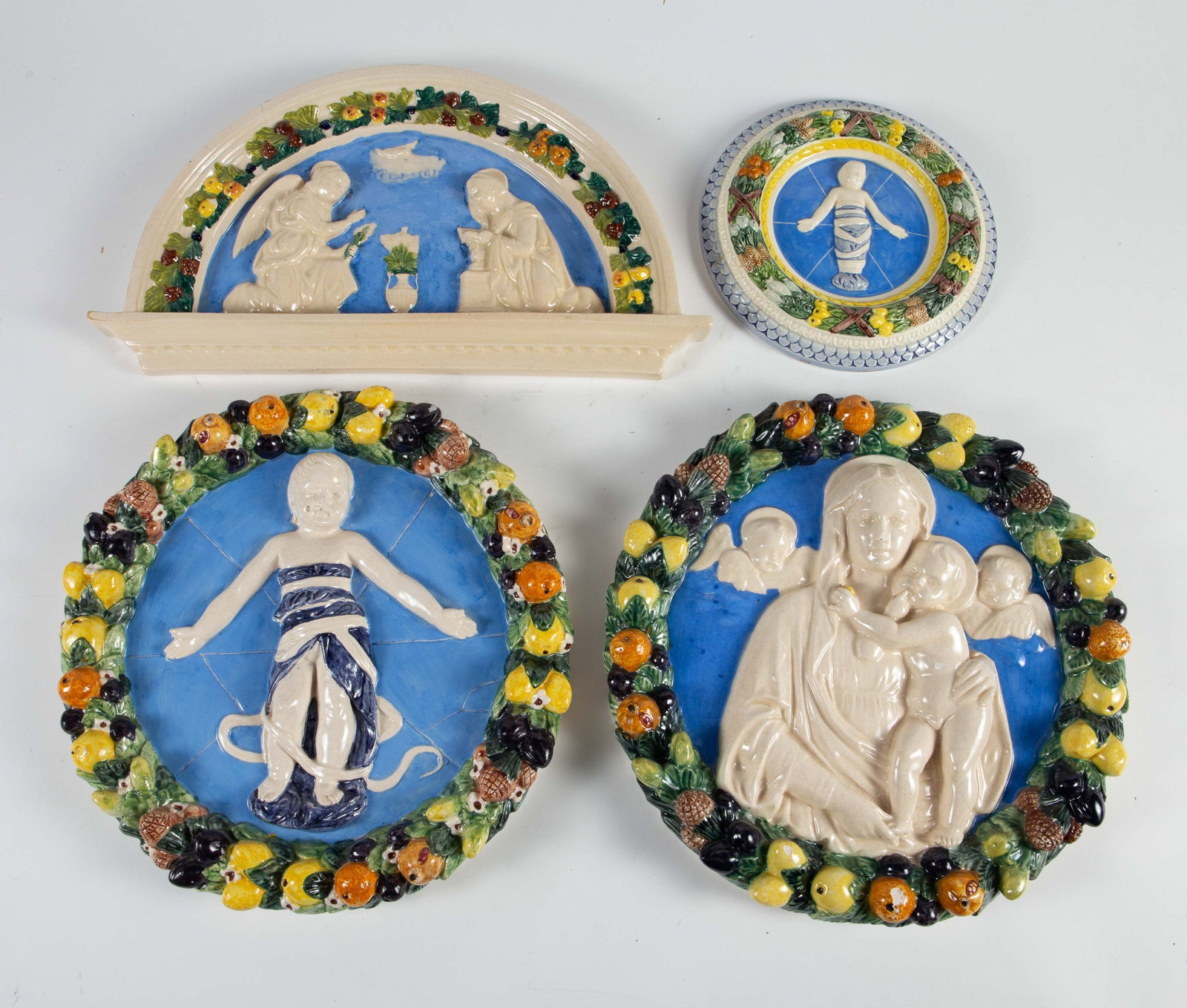 4 Pc. Lot of Della Robbia Style Majolica Pottery.: These plaques look to be in overall good condition, with some chips present. The subjects include children/Putti, Madonna with child, and angels. The largest plaque measures 12 3/4" x 12 3/4" x 2".