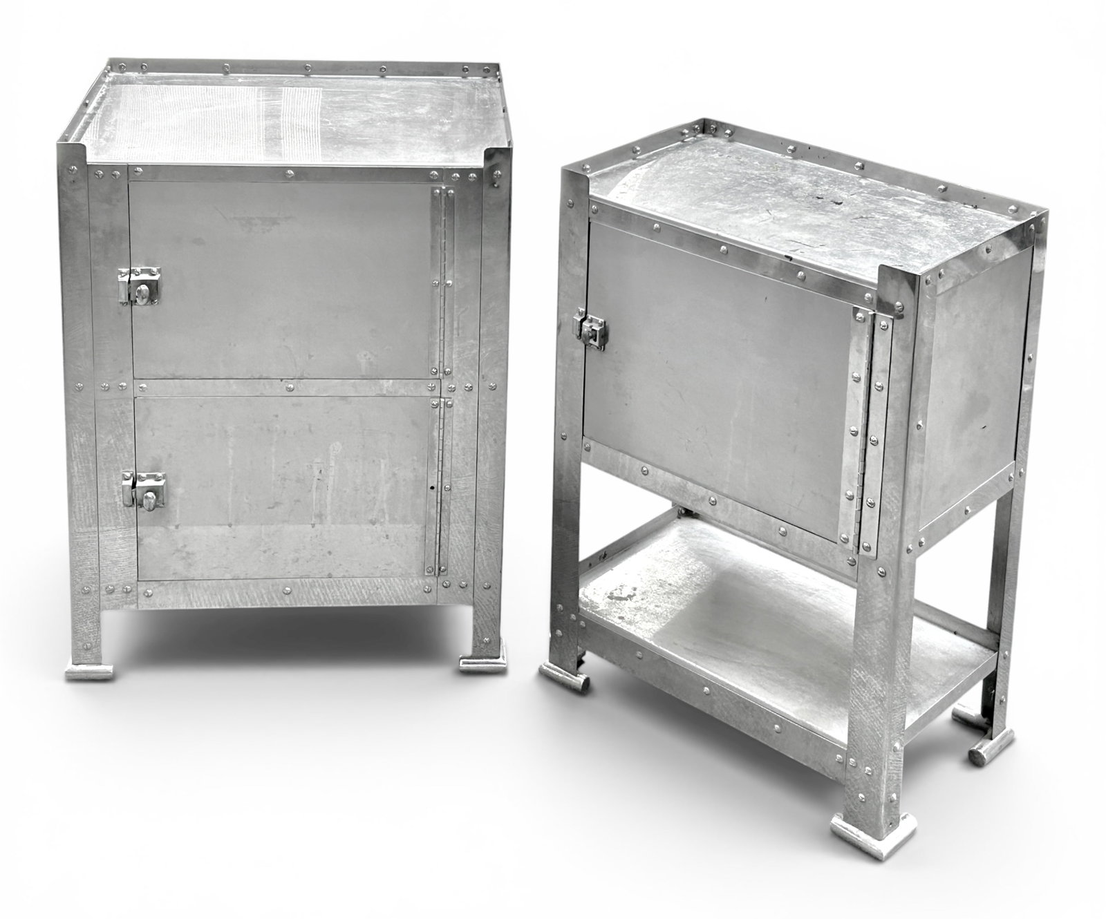 Lot of 2 Industrial Steel Cabinets.: The lot contains 2 aviator style polished steel storage cabinets, seemingly from the same set. They both have gallery tops and plated brass latches. The smaller cabinet has one door with storage