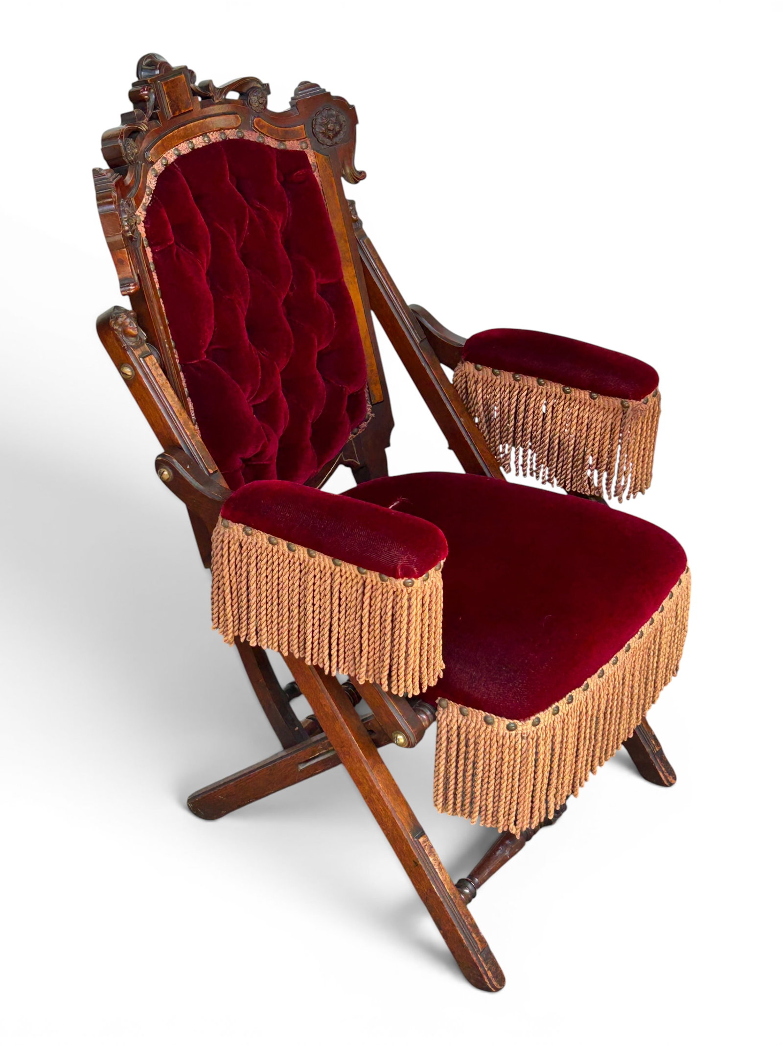 Victorian Upholstered & Carved Folding Chair.: This antique Renaissance Revival chair has dark purple upholstery with nailhead trim and tassels. The back is button tufted. There is a tear on the seat and a few of the tassels on the arms are