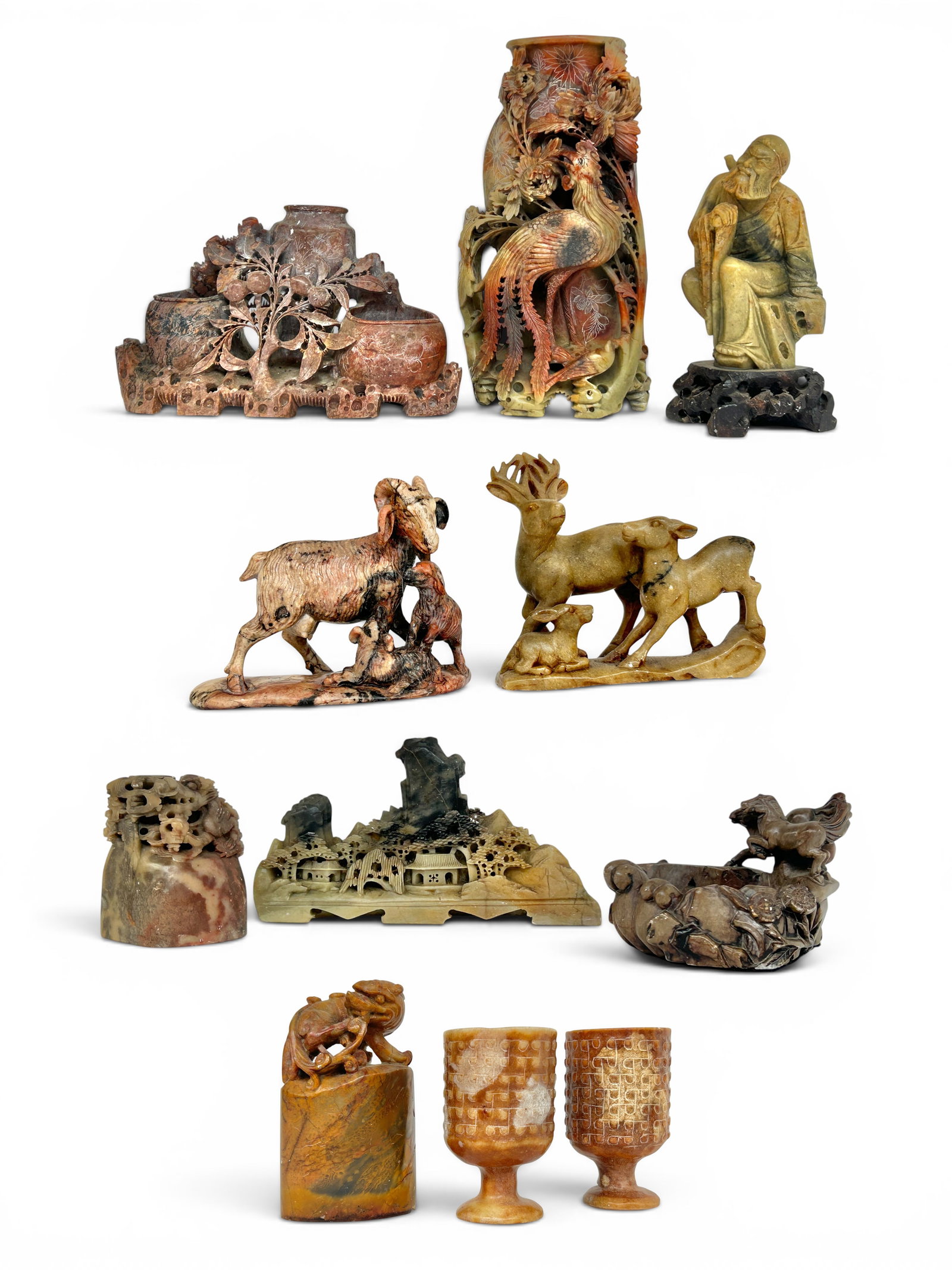 Lot of 11 Vintage Chinese Soapstone Carvings.: The lot includes 2 footed cups, 2 seals, a tall vase, a triple vase, a landscape, a deer sculpture, a ram sculpture, an ink pot, and a figural piece depicting an old man. The smallest item measures 3 