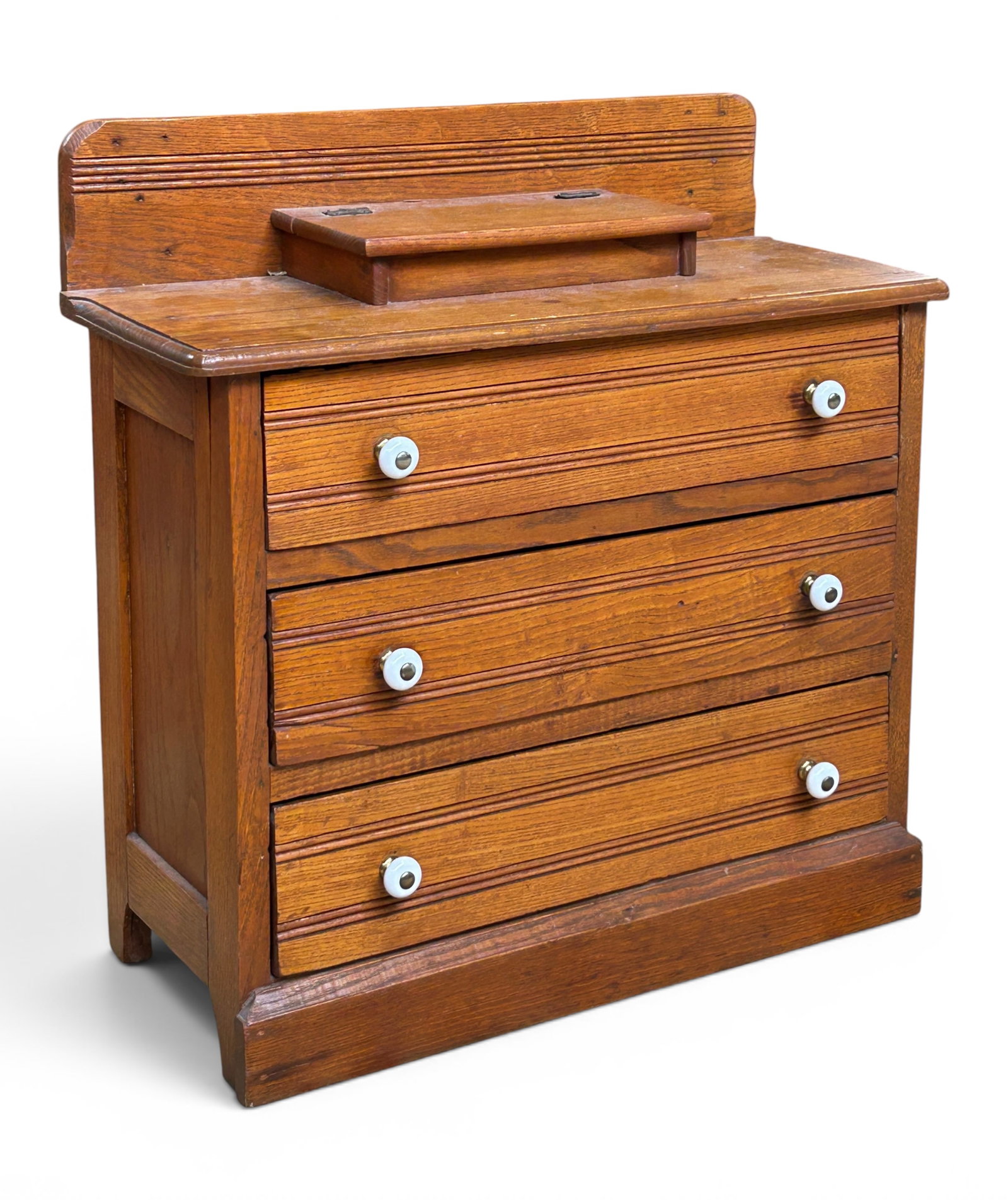 Victorian Miniature Apprentice Table Top Chest: The chest has 3 drawers with porcelain pulls, a backsplash, and a lift top storage compartment on the top. The interior of the drawers are painted light blue, and the original turned wood pulls are