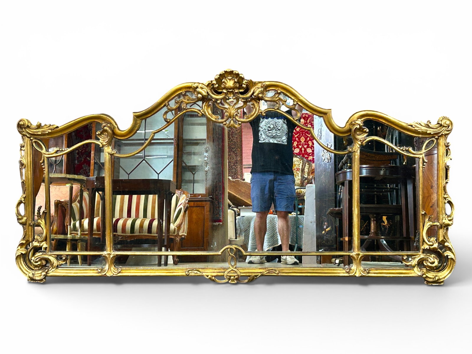 Antique Ornate Carved Gilt Overmantel Mirror.: The large mirror is divided in 3 sections, and has intricate relief carvings on the border and overlay on the mirror. It has a grand crest with a central shell or fan, and scroll work. The piece