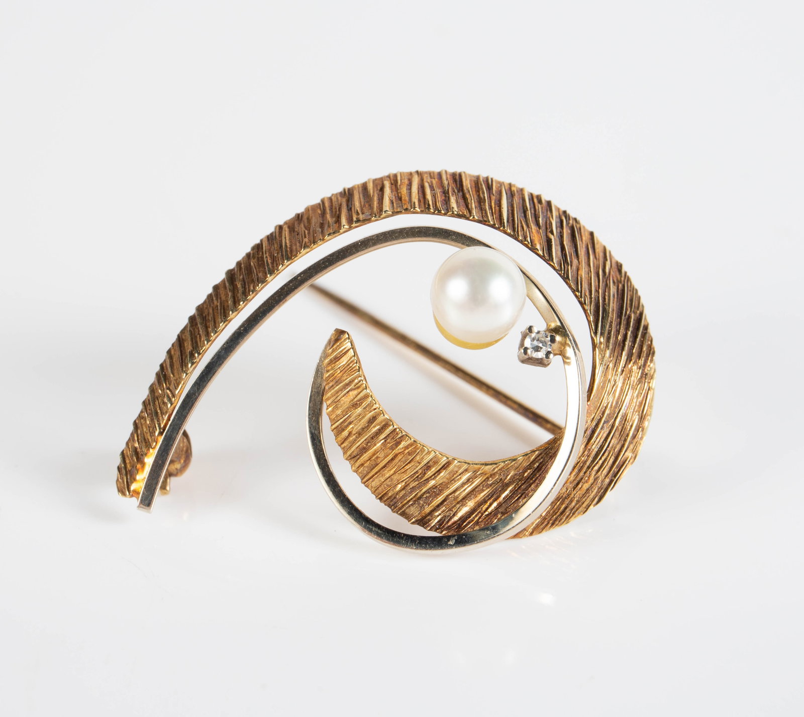 14K Two-Tone Gold, Pearl & Clear Stone Brooch.: The brooch is marked 585 on the backside. It features a yellow gold textured swirl, accented by a white gold swirl, a pearl, and a small clear stone (not a diamond). The pin weighs 2.3 Pennyweight,