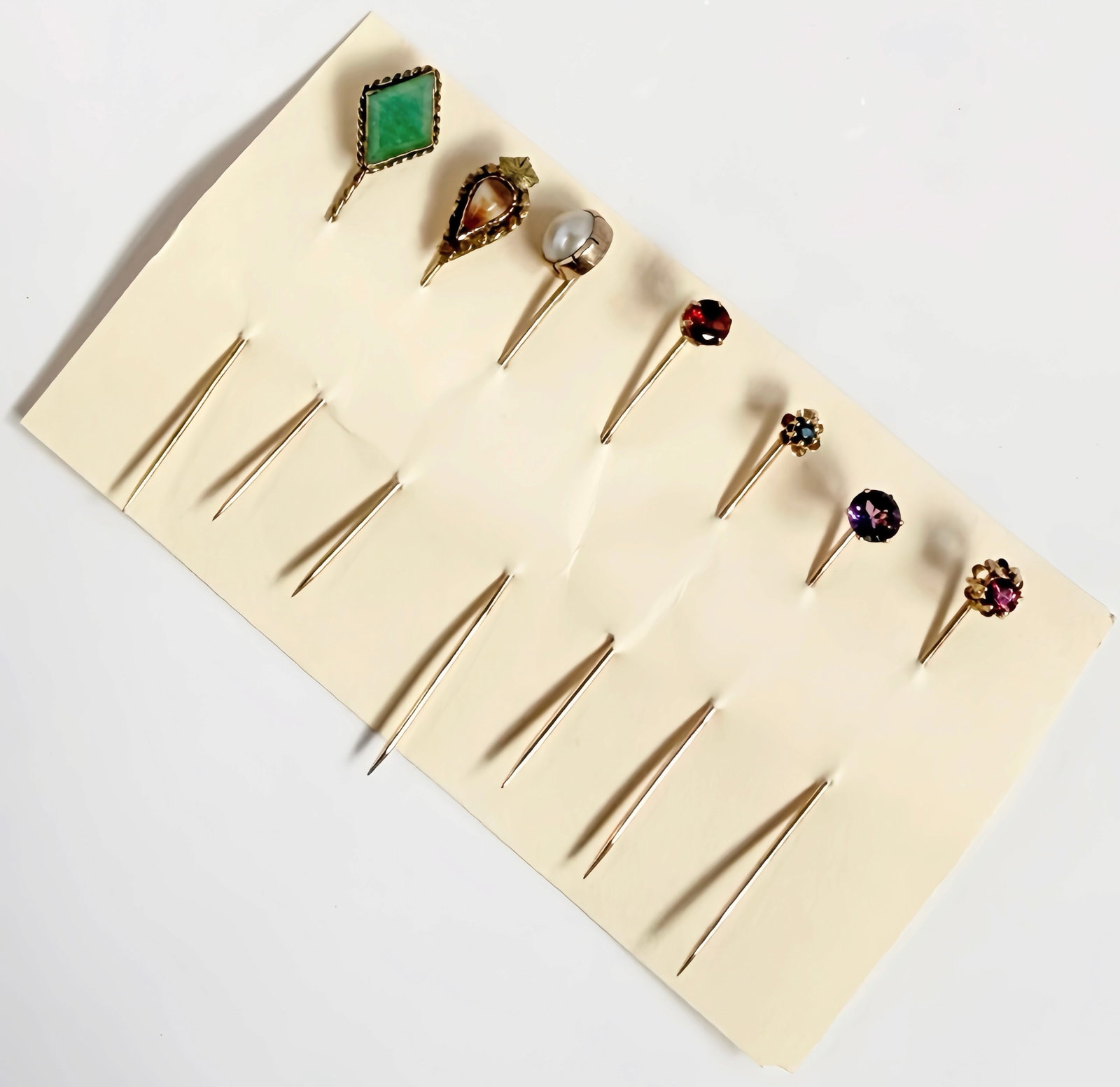 7 10K & 14K Gold Stick Pins - Jade, Garnet, Pearl.: The lot contains 7 antique or vintage stick pins. The stones included are garnet, pearl, sapphire, jade, amethyst, and more. The Jade pin is marked 18 HPK on the back, but tested appropriately for