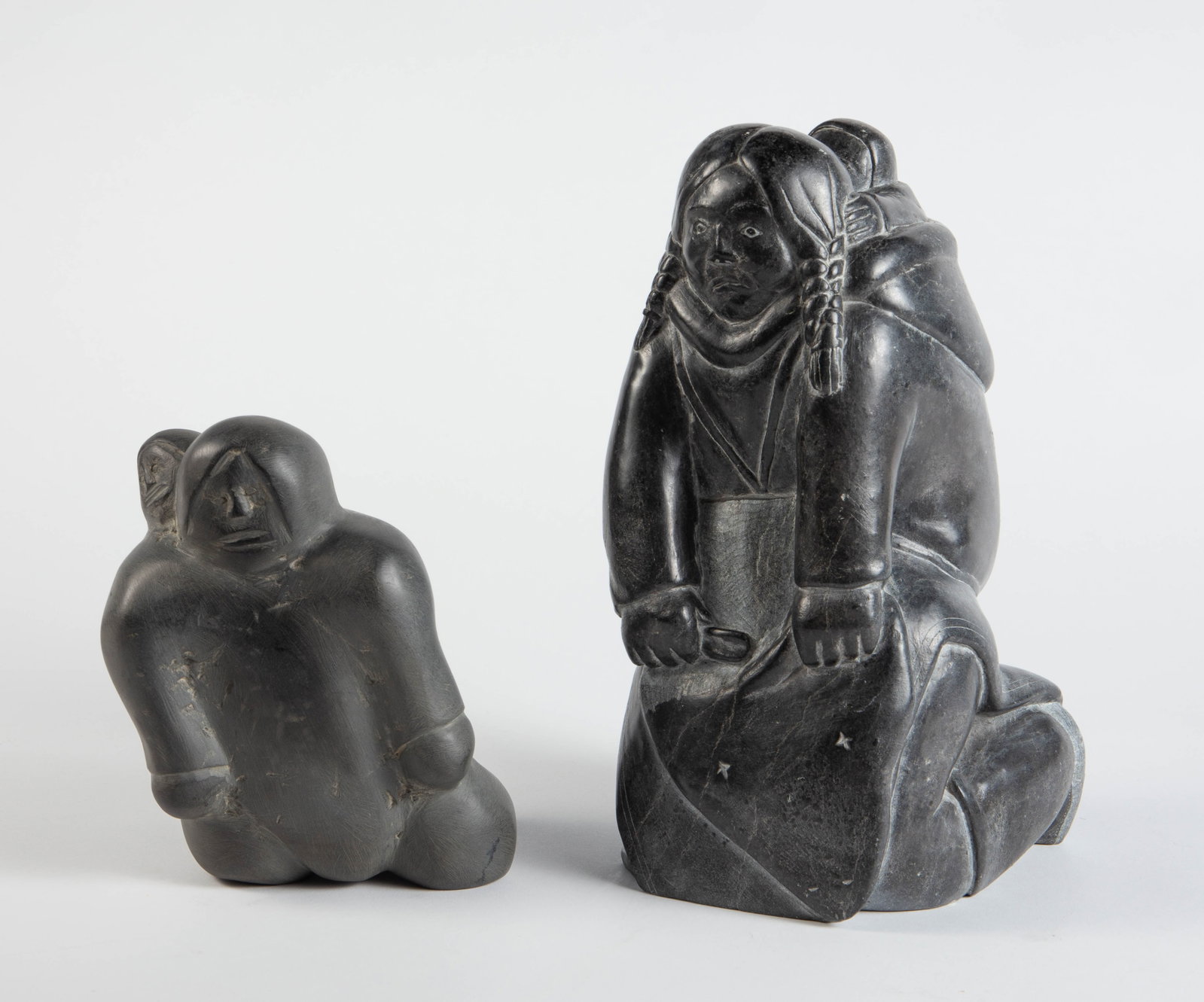Lot of 2 Carved Inuit Sculptures, Including Erkok.: Both sculptures depict mothers carrying their children. They look to be in overall good condition. The larger sculpture is signed, "D. Erkok". It measures 5 1/2" x 6 3/4" x 11". The smaller sculpture