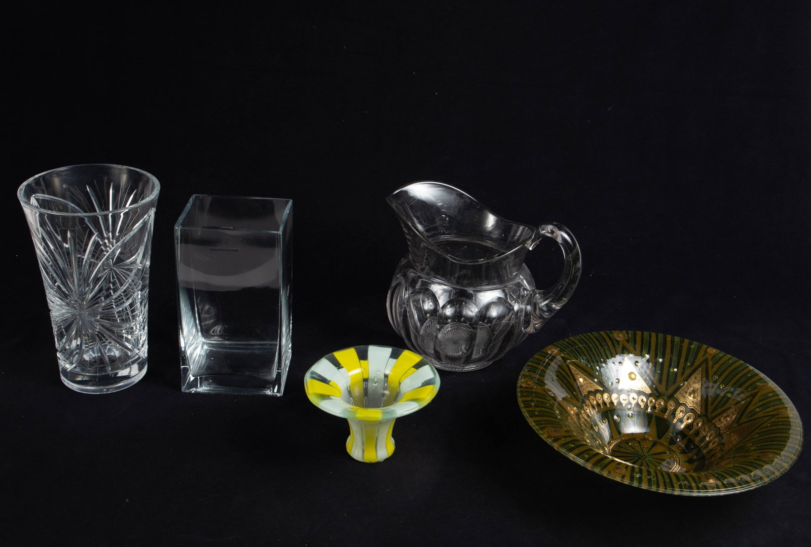Lot: 5 Glass Items, Including Higgins.: The green and gold bowl and the smaller yellow and white vase are both Higgins (signed). The rectangular vase is made in Poland, and the other two items appear to be unmarked. The pitcher has several 
