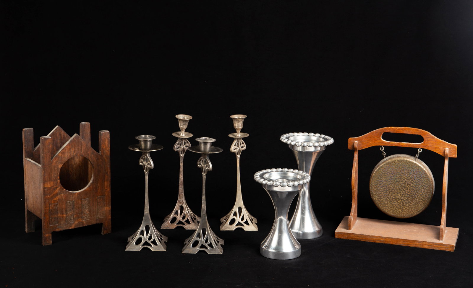 Lot: Art Nouveau Candlesticks, Dinner Bell, etc.: This lot includes two pair of Art Nouveau candlesticks, a more contemporary set of two aluminum candlesticks, a dinner gong, and what may be the wood body of a small mantel clock. Overall, the lot loo