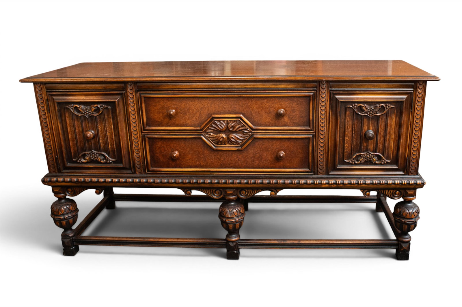 Berkey & Gay Tudor Style Carved Oak Buffet: The buffet or sideboard has multiple carvings of flowers and drapes, carved legs, stretchers, and knobs. It has 2 large drawers, 2 doors with small interior drawers, and a storage area. It measures