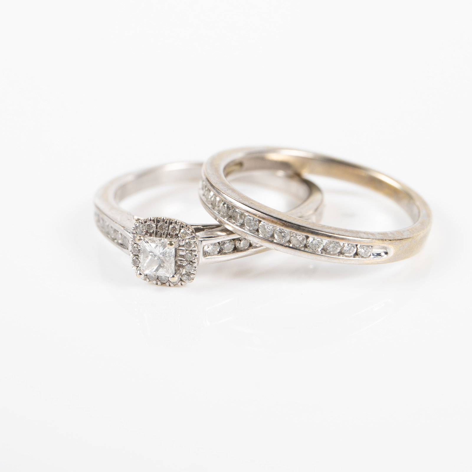 14K White Gold & Diamond Wedding Set.: The lot contains a set of two 14K white gold rings with brilliant diamonds. They are both marked 14K inside the bands. The engagement ring features a 3mm square cut diamond surrounded and flanked by s