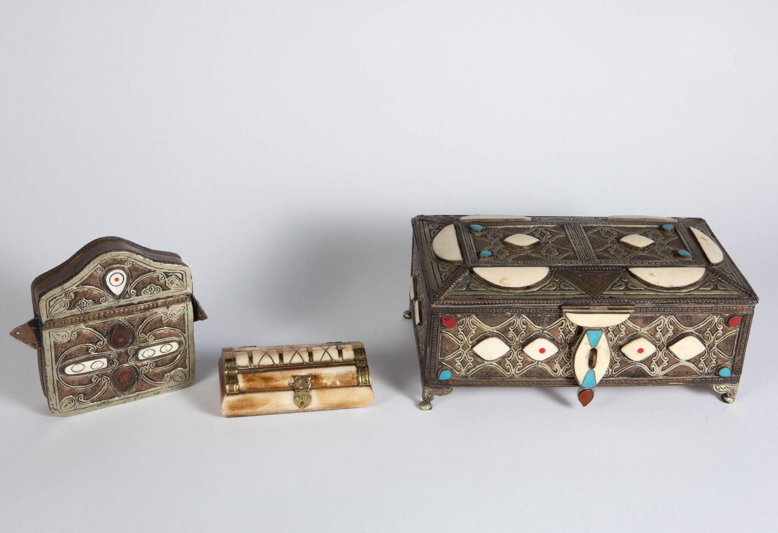 Lot of 3 Moroccan Tooled Brass & Bone Boxes.: The lot contains 3 likely antique Moroccan boxes. There is a hinged jewelry box with inlaid bone and turquoise and red inlaid sections; a brass and silverplate Koran case or talisman holder with a hin