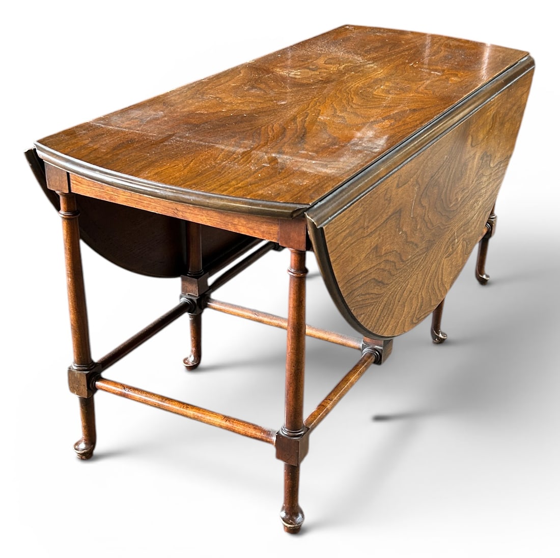 Baker Small Antique Dropleaf Table.: This burled walnut gateleg table has two dropleaf sides, six legs, and a stretcher base. It is in good overall condition, with some wear. The piece measures 37" wide, 15" deep, and 18" tall. Each