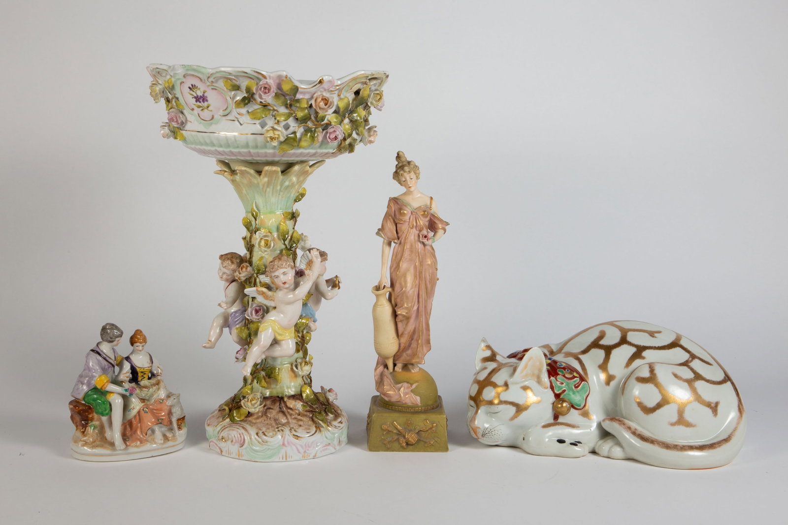 Lot: Japanese Cat, Cherub Compote, Figurines.: The sleeping cat and countryside couple are both made in Japan. The woman holding a water jug is marked as Austrian. The largest item in the lot is the cherub compote, in As Is condition. It measures 