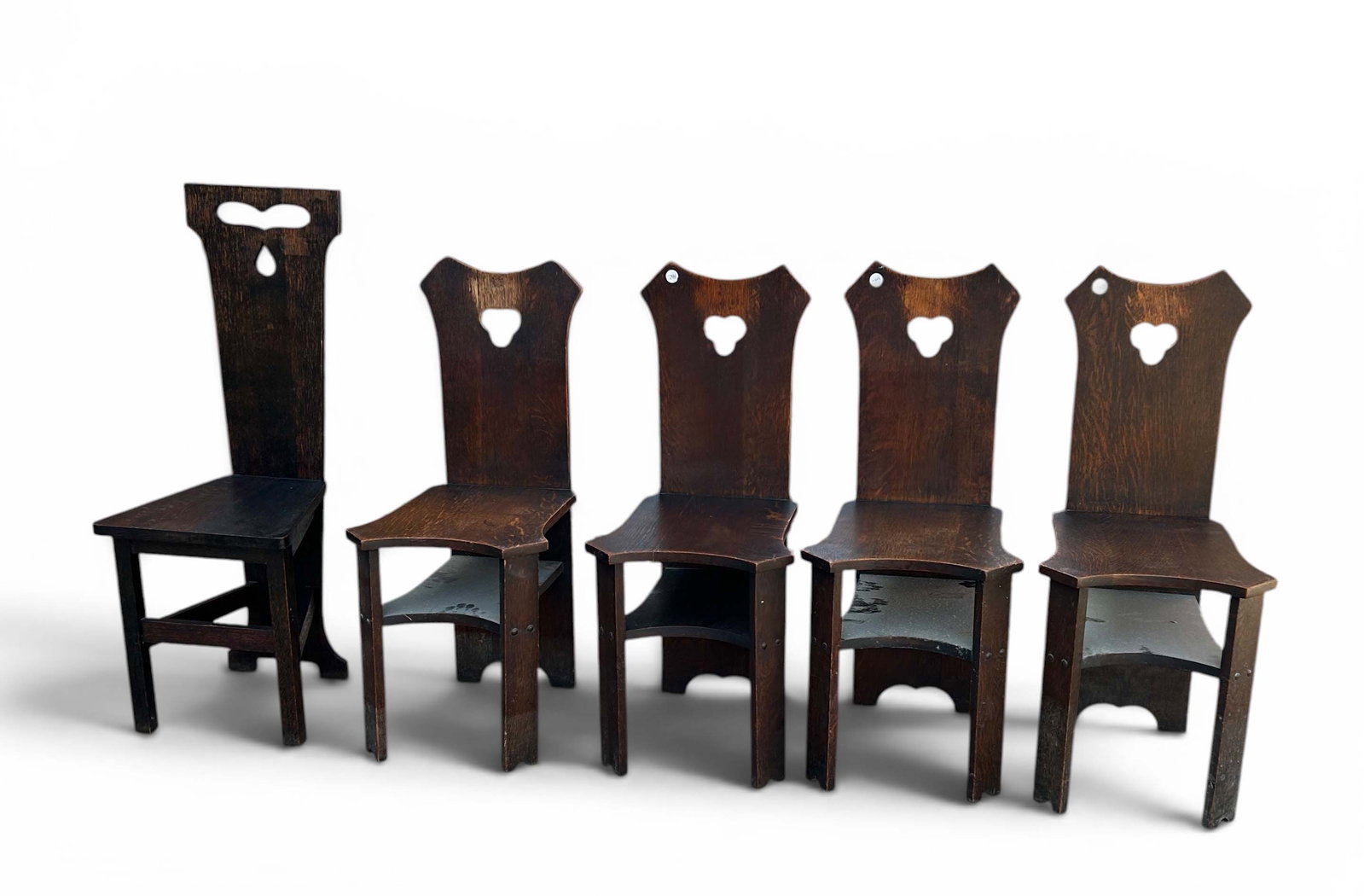 5 Arts & Crafts Carved Cutout Hall Chairs.: The lot contains 4 matching Mission or Arts & Crafts style chairs and a singular chair. The matching chairs have a lower tier under the seat, and 3-leaf clover style cutouts on the backs. The