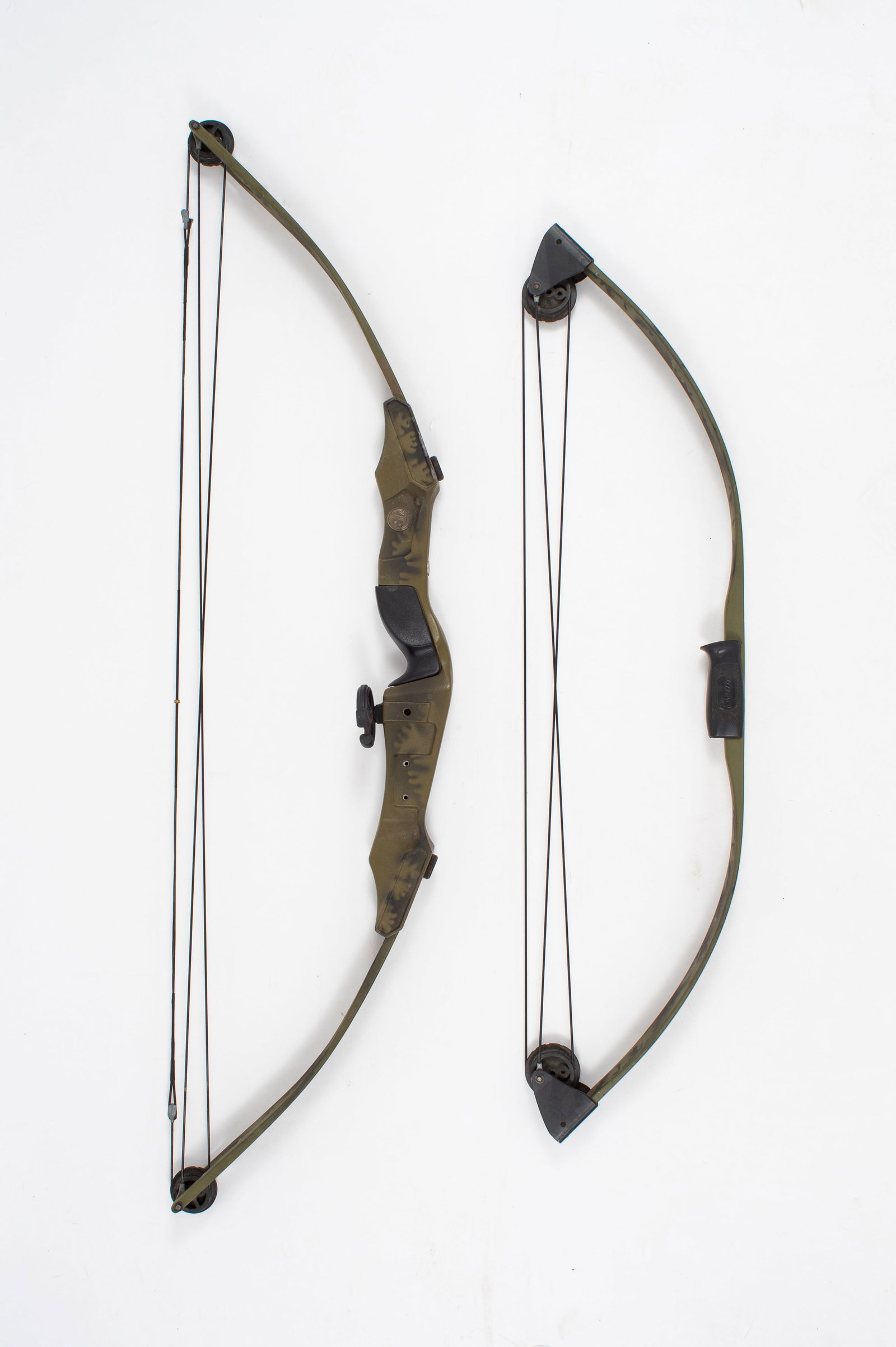 2 Bear Archery Bows - Black Bear & Sun Bear.: The lot contains 2 camouflage decorated archery bows by Bear Archery. The largest bow is a vintage Black Bear bow. It has a draw length of 26", a draw weight of 45 Pounds, and an ammo compound string 