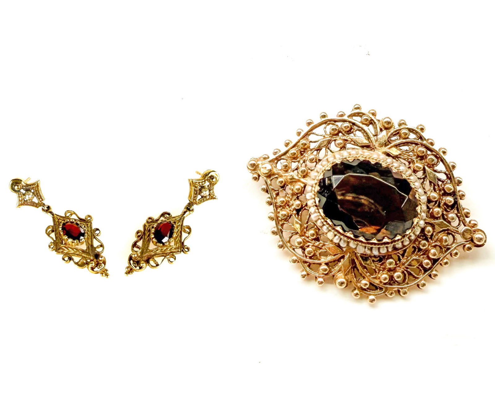 14K Gold Smoky Quartz Brooch & Garnet Earrings.: The lot contains 2 pieces of 14K gold items. There is a brooch with a large oval smoky quartz stone. The large stone is surrounded by seed pearls in a filigree setting, having many small spheres or do