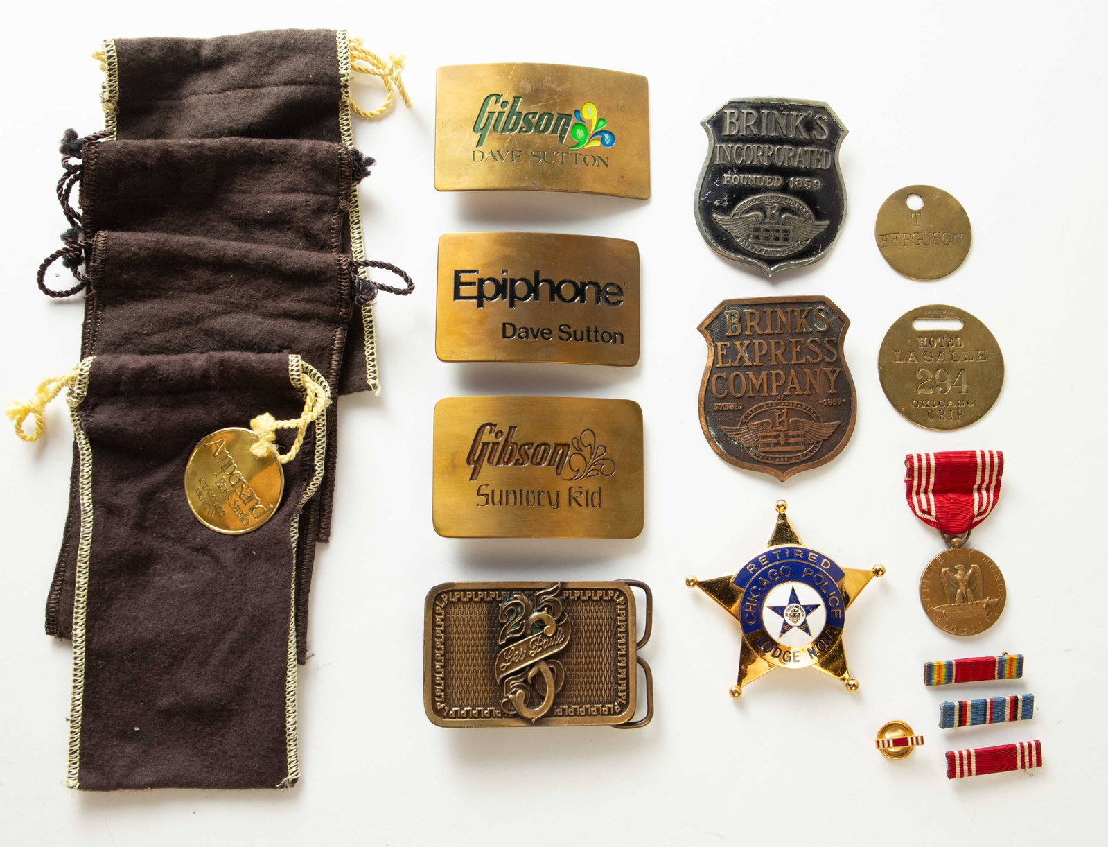 Lot: Retired Chicago PD, Military Badges, Buckles.: The lot contains 13 items. There are 4 music-related belt buckles, 2 Brink's Incorporated badges, a Retired Chicago Police badge, a couple of brass tags (including the Hotel La Salle), a U.S. Military