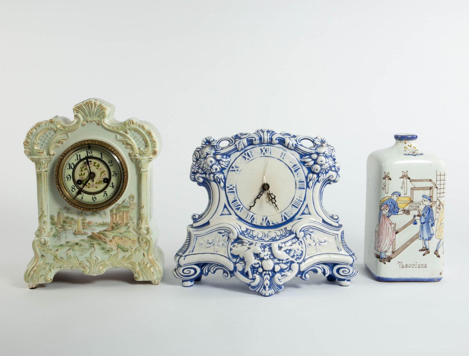 Lot: Deruta Bottle, Porcelain Clocks.: The clocks are untested. One is a blue and white clock with flowers and fruit; the other is a mantel clock with a seaside scene. The Italian Deruta pottery bottle has a painted treasury scene.