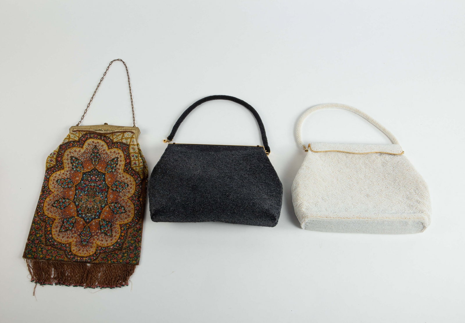 Lot: Antique & Vintage Beaded Handbags.: There are two vintage beaded handbags with similar designs- one is black, the other is white. The black purse has a label that reads, "Lutheran World Service Crafts Made in Hong Kong". Each of these