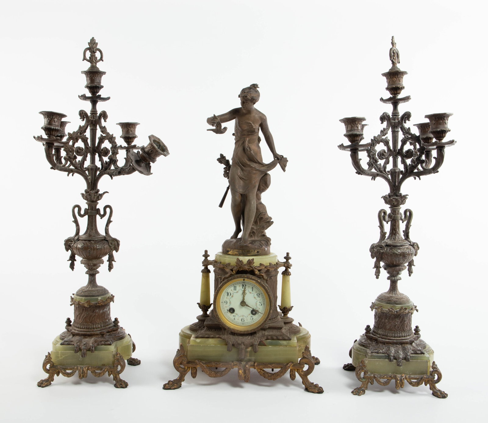 After Ferrand "Prisonniere" Clock Set, As Is.: This antique 3-piece onyx and metal clock set consists of a figural clock after Ferrand's "Prisonniere" (working condition unknown, key is included), and a pair of 4-arm pawfoot candelabra. One is As