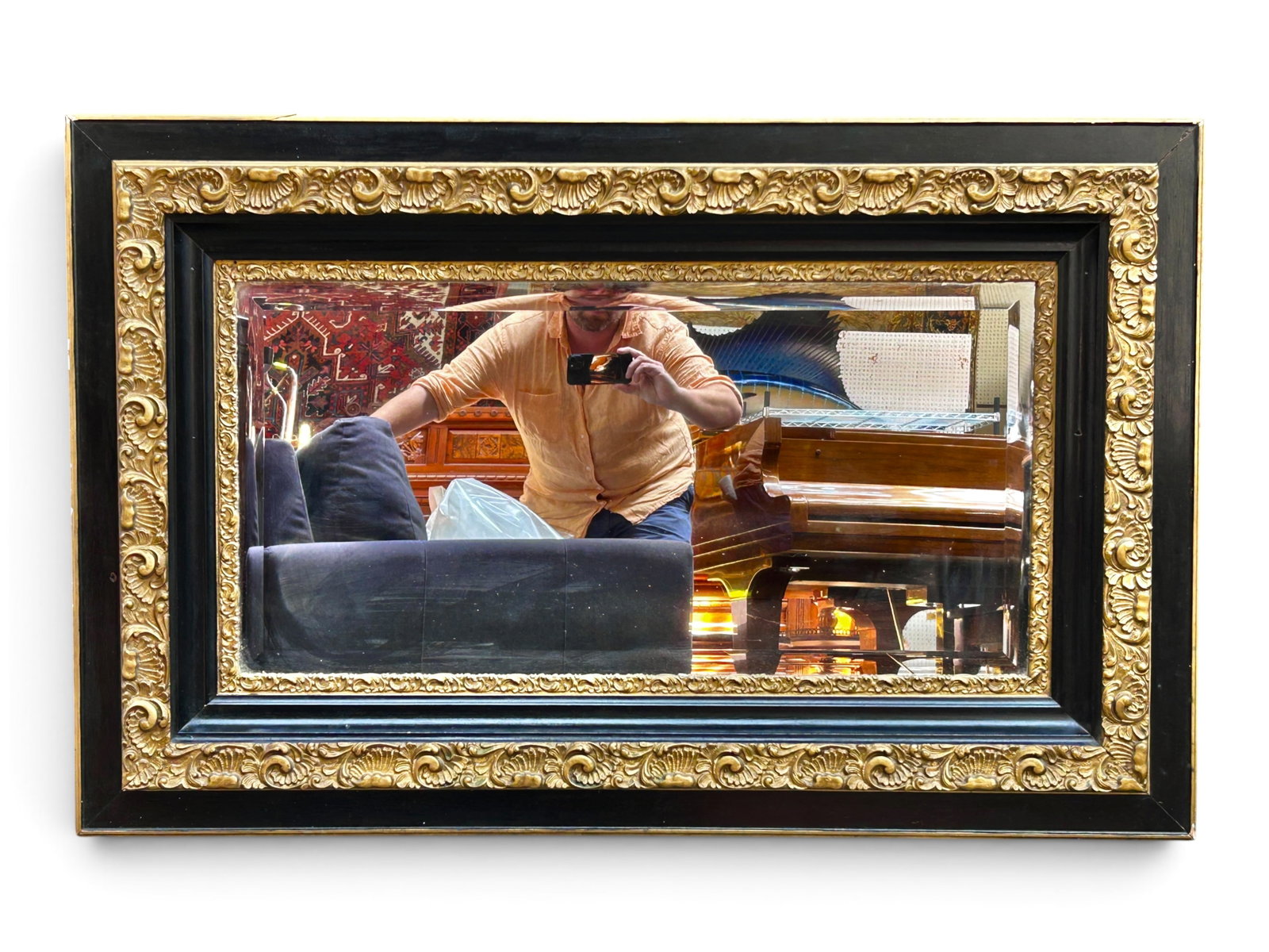 Ornate Black & Gilt Wall Mirror.: The bevelled mirror has a wide frame with ornate molded and gilded sections and black painted sections. It measures 49 3/4" x 31 3/4". There are some chips, scratches, and stains on the piece, as well