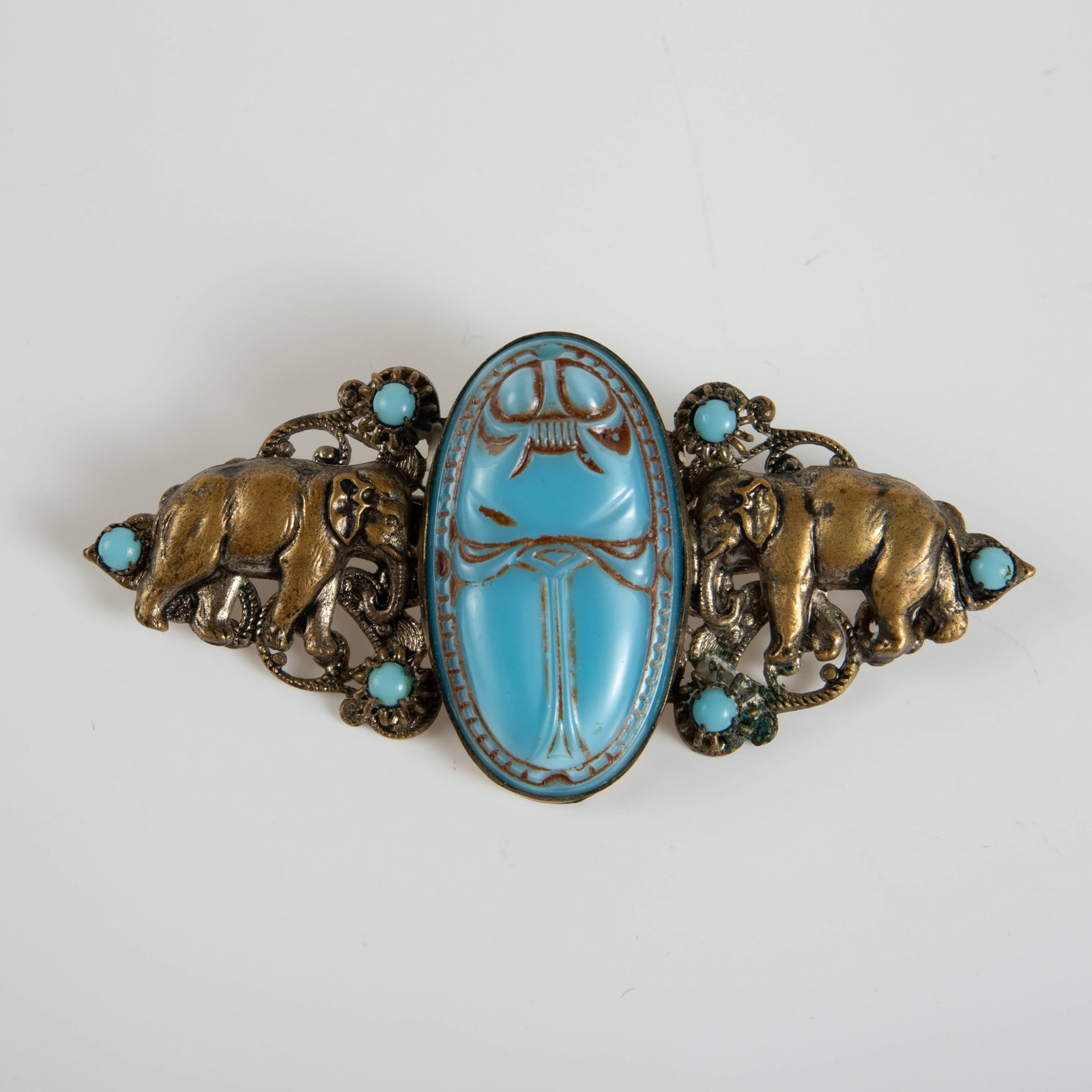 Egyptian Revival Czech Brooch, Neiger Bros.: The brooch, circa 1920's, is marked Czechoslovakia on the back. It is attributed to the Neiger Brothers. It features two elephants facing a central etched blue opaline glass scarab. It measures 2 7/8"