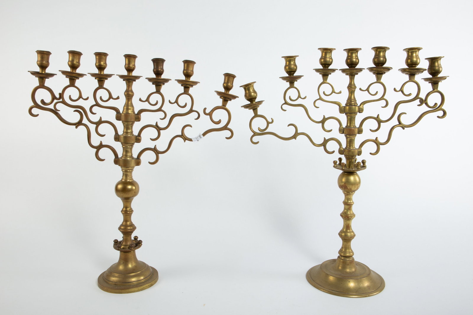 Pair of Bronze 7-Arm Judaica Temple Menorahs.: The heavy candelabras have different bases and matching arms. The slightly taller one measures 21 1/4" tall, 18 1/4" wide, and 7 3/8" deep. Some of the arms will need to be adjusted, and there are