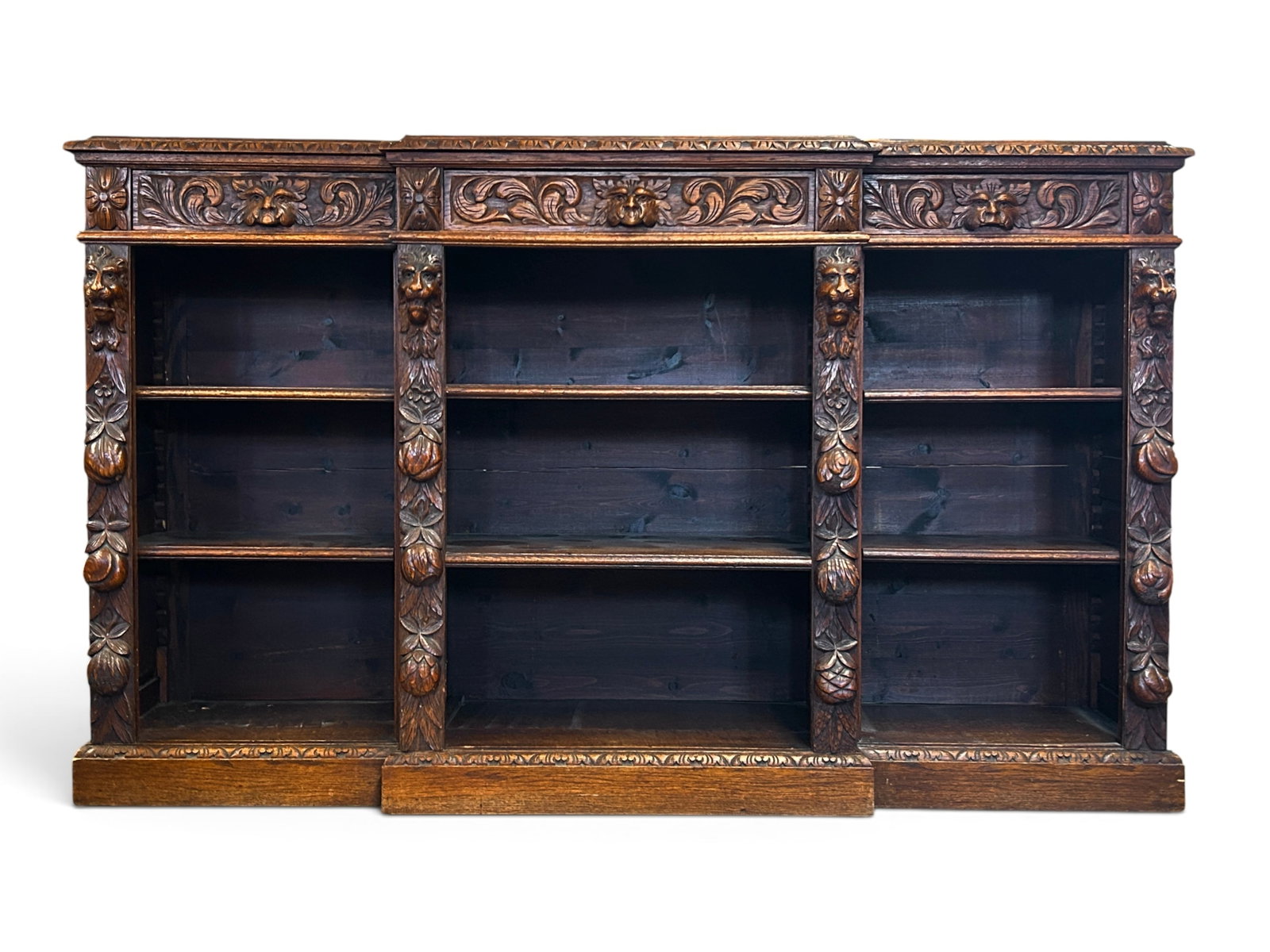 Heavily Carved Antique Bookshelf w/ Faces.: The piece of furniture features high relief carved lion faces, fruit, North Wind faces, flowers, and patterns. It has 3 sections, each with 2 adjustable shelves inside. There are 3 drawers along the t