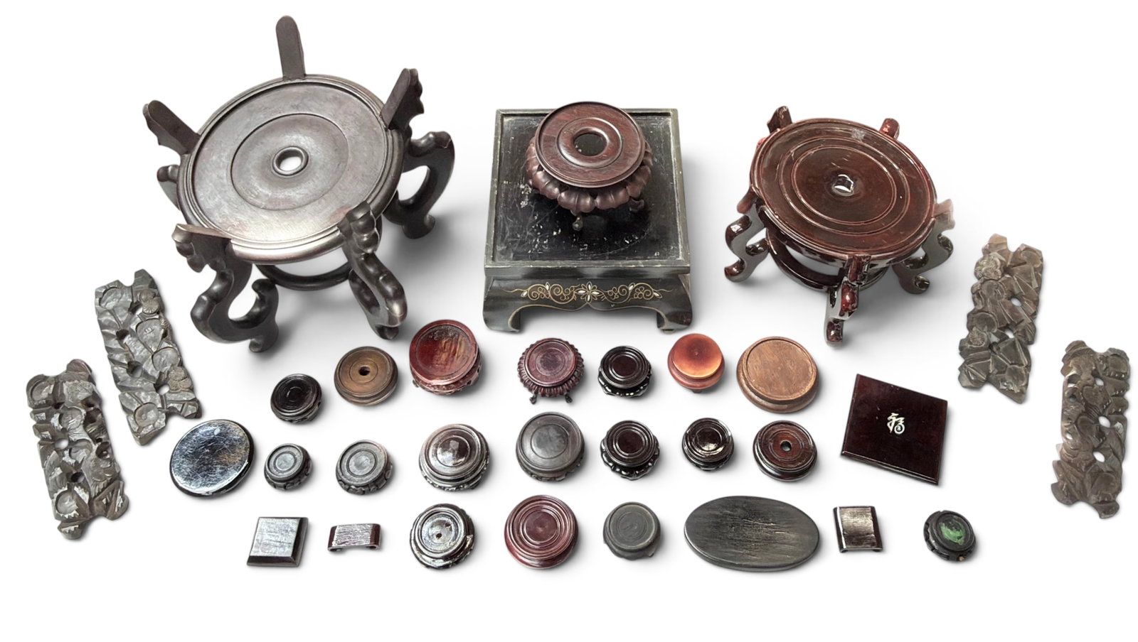 Asian Carved Wood Stand Assortment.: The lot contains 32 items, mostly Chinese. Most of the stands are round, and 4 of them are rectangular. The largest stand, which has one of its legs repaired, measures 11 3/4" tall and 15 1/2" in diam