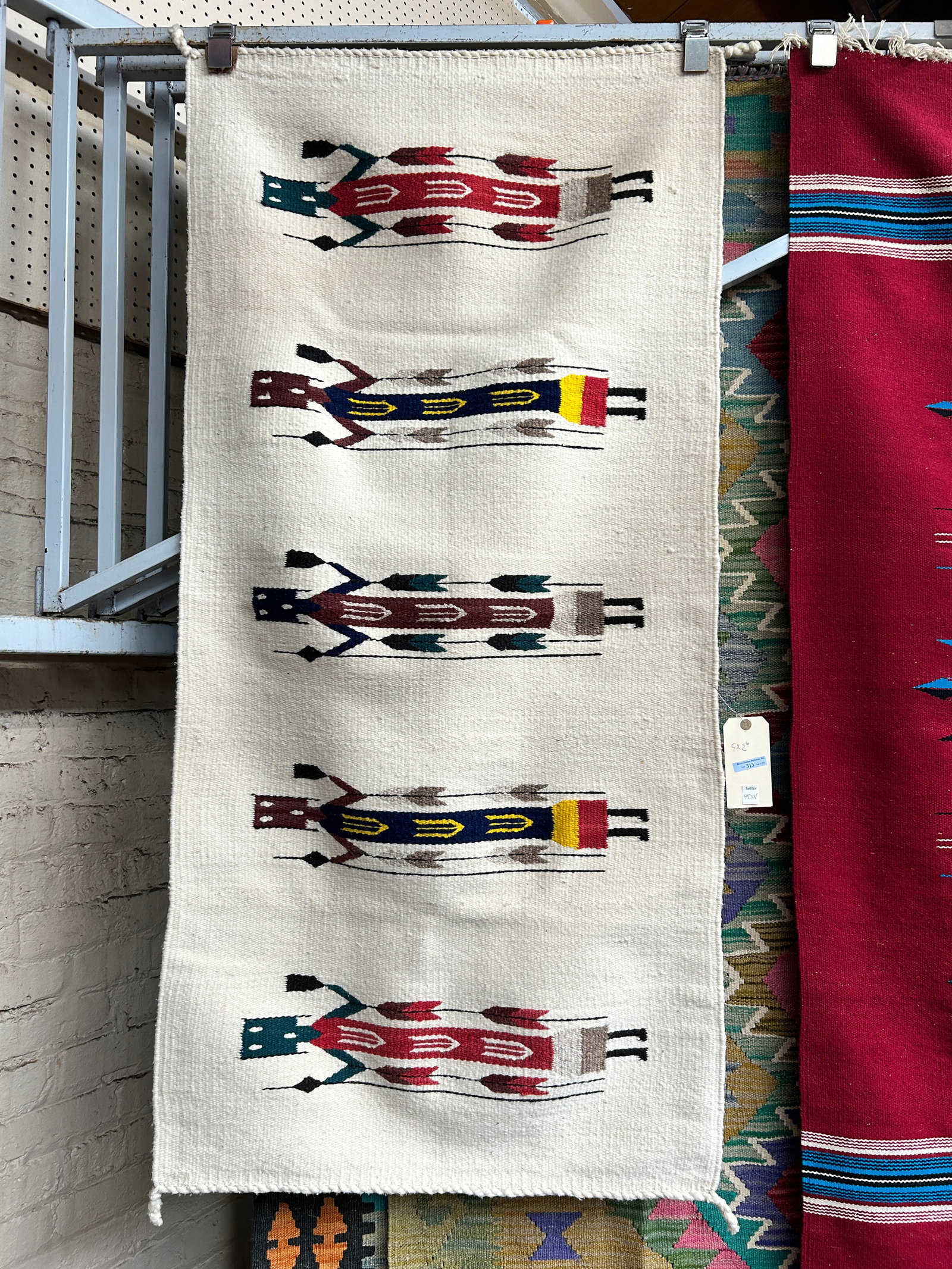 2' 6" x 5' Navajo Yei Rug.: The rug has loops on the back, as it had previously hung on a wall. It looks to be in good overall condition. In-house shipping is available. To receive the best shipping rate on this item, please