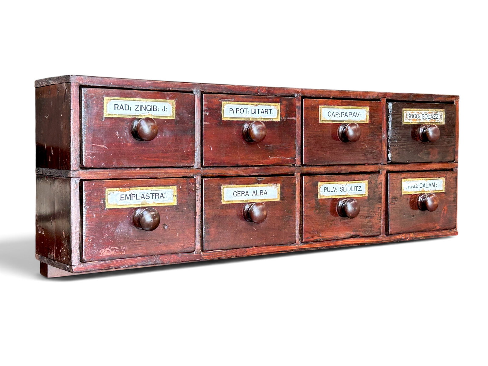 Antique 8-Drawer Tabletop Apothecary Cabinet.: The dark wood cabinet has round wood pulls, and nameplates with medicinal ingredient labels. It has a wooden lip on the back to allow for the cabinet to be secured onto the back of a desk or table. Th