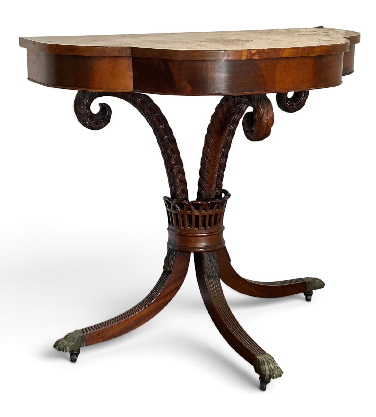 Mahogany Demilune Table w/ Bronze Paw Feet.: The likely antique table has 3 curved legs with brass paw feet and casters, and three scrolled foliage style carvings connecting to the table. The foliage carvings and the legs connect at the center