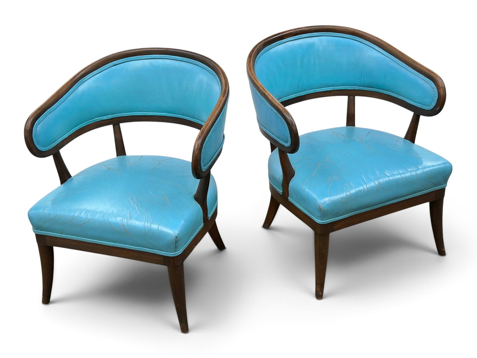 Pair of Mid Century Wood Frame Barrel Chairs.: The pair of comfortable chairs have dark wood stylized frames with very slightly curved tapered legs. They are upholstered in a turquoise colored vinyl, which has many discolored cracks and creases on