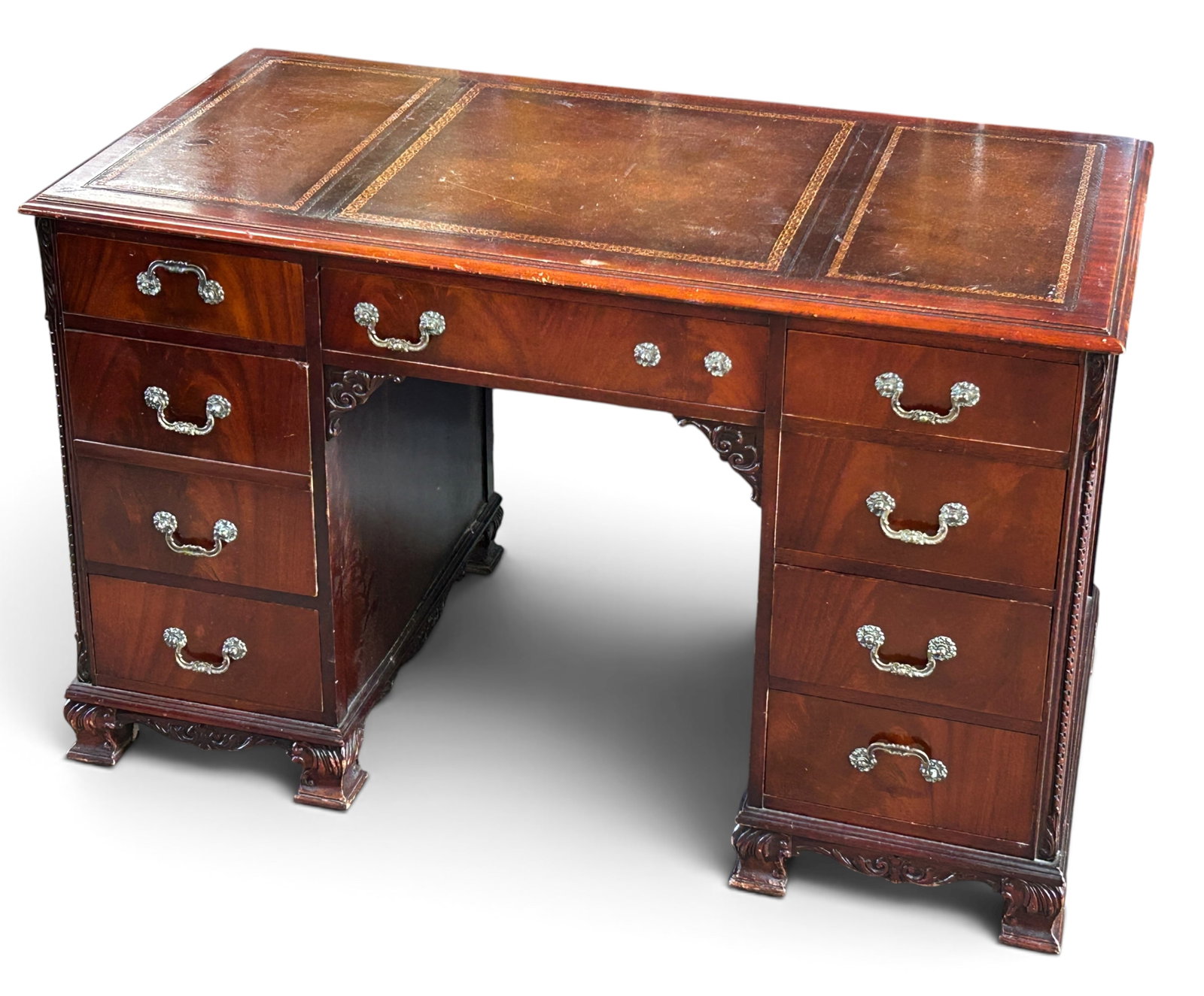 Vintage Flame Mahogany Kneehole Desk.: The desk has a tooled leather top, eight drawers with brass hardware, and bracket feet. One of the pulls is missing. The top has some wear. Overall it is in good, sturdy condition. It measures 48 1/2"