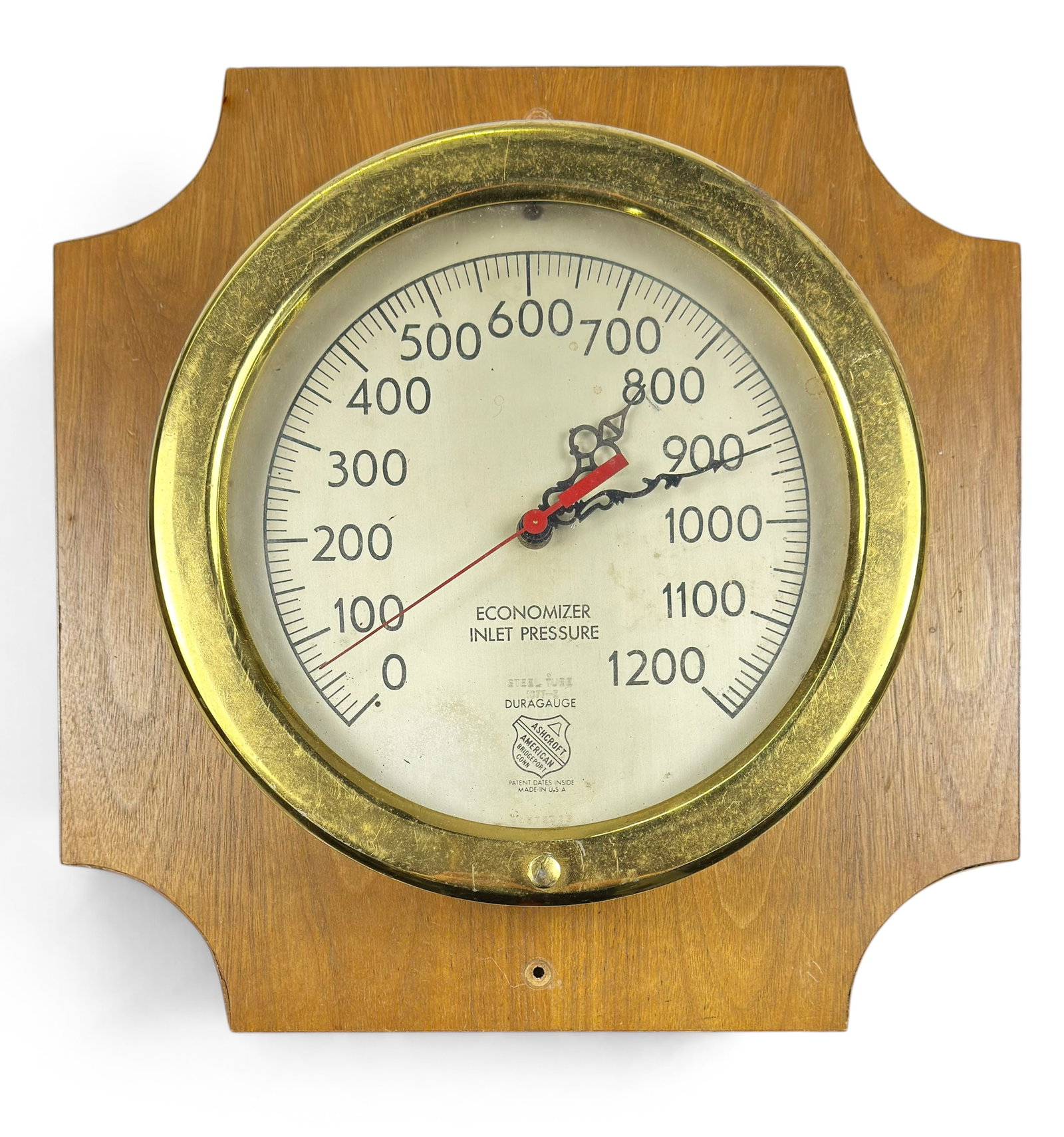 Ashcroft Brass Duragauge Pressure Gauge, 0-1200.: This vintage industrial bourdon-tube pressure gauge or economizer inlet pressure gauge is mounted on a wooden board for wall mounting. It is marked 1077-E over the Duragauge label. The brass bezel mea