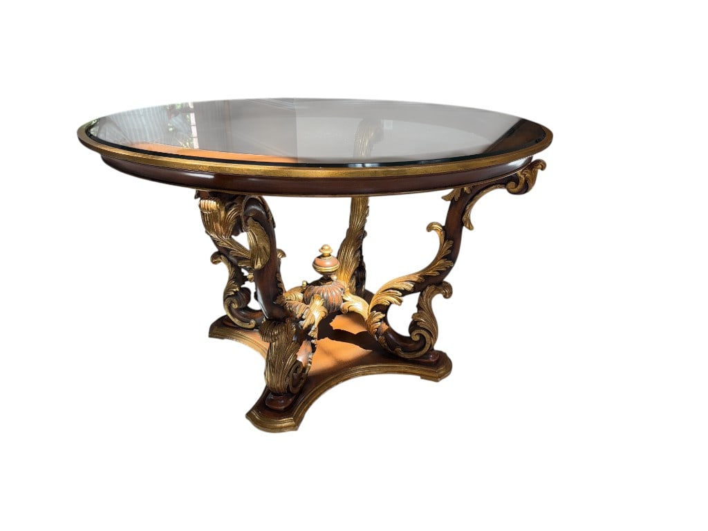 $6,000+ Italian Ornate Glass-Top Console Table with Gold Leaf Accents, 30"H: $6,000+ Italian ornate round console table featuring a glass top with intricate gold leaf accents. Supported by a beautifully crafted base, the table showcases elegant scrollwork and leaf patterns in