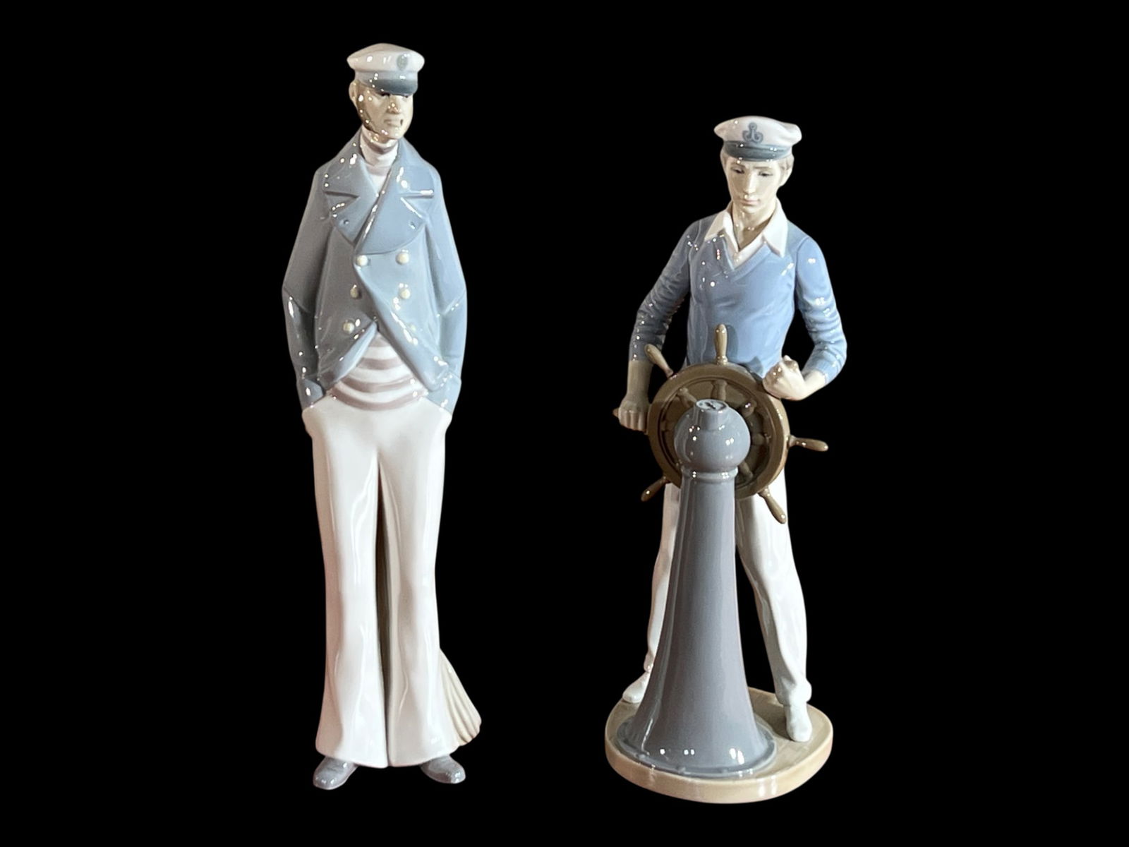 Lladró (Spain), Nautical Sailor/Sea Captain Porcelain Figurines, DAISA Mark (Pair), 15" H: A matched pair of Spanish glazed porcelain figurines by Lladró, modeled as maritime figures in crisp, elongated silhouettes and finished in restrained nautical tones. The standing figure, in a pale-b