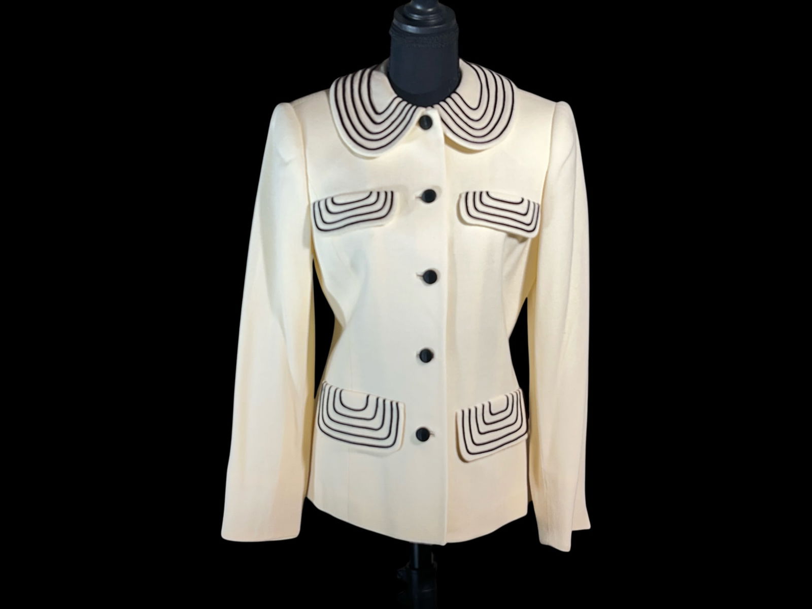 David Hayes Vintage Ivory Wool Jacket with Black Piped Appliqué Collar and Pocket Flaps, Size 8: A vintage David Hayes tailored ladies’ jacket, executed in an ivory wool suiting with striking black piped appliqué detailing in a concentric, graphic motif. Cut in a structured, hip-length silhoue